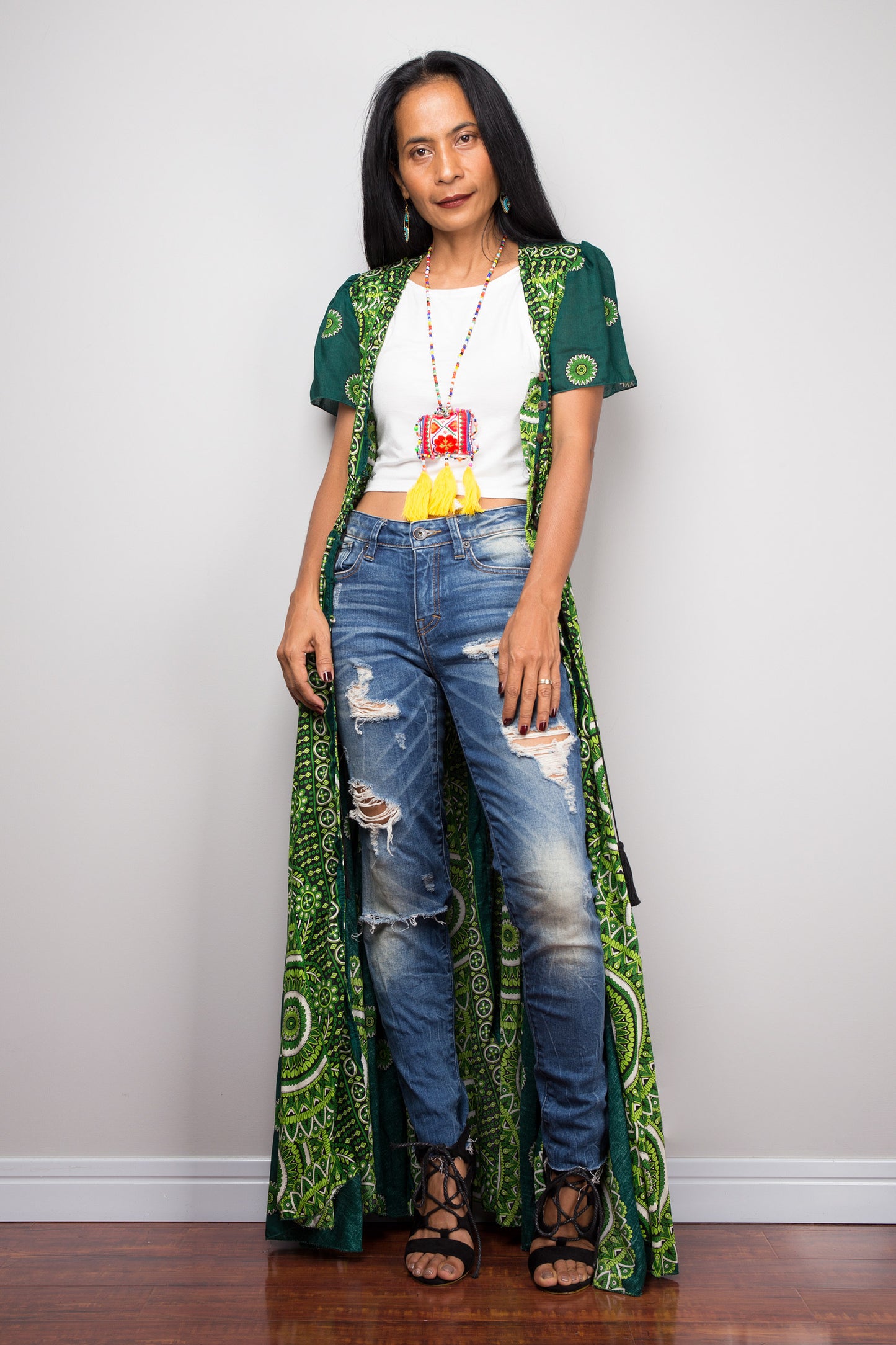 Woman wearing a green patterned outfit with a white top and ripped jeans on a plain background.  Nuichan button summer dress