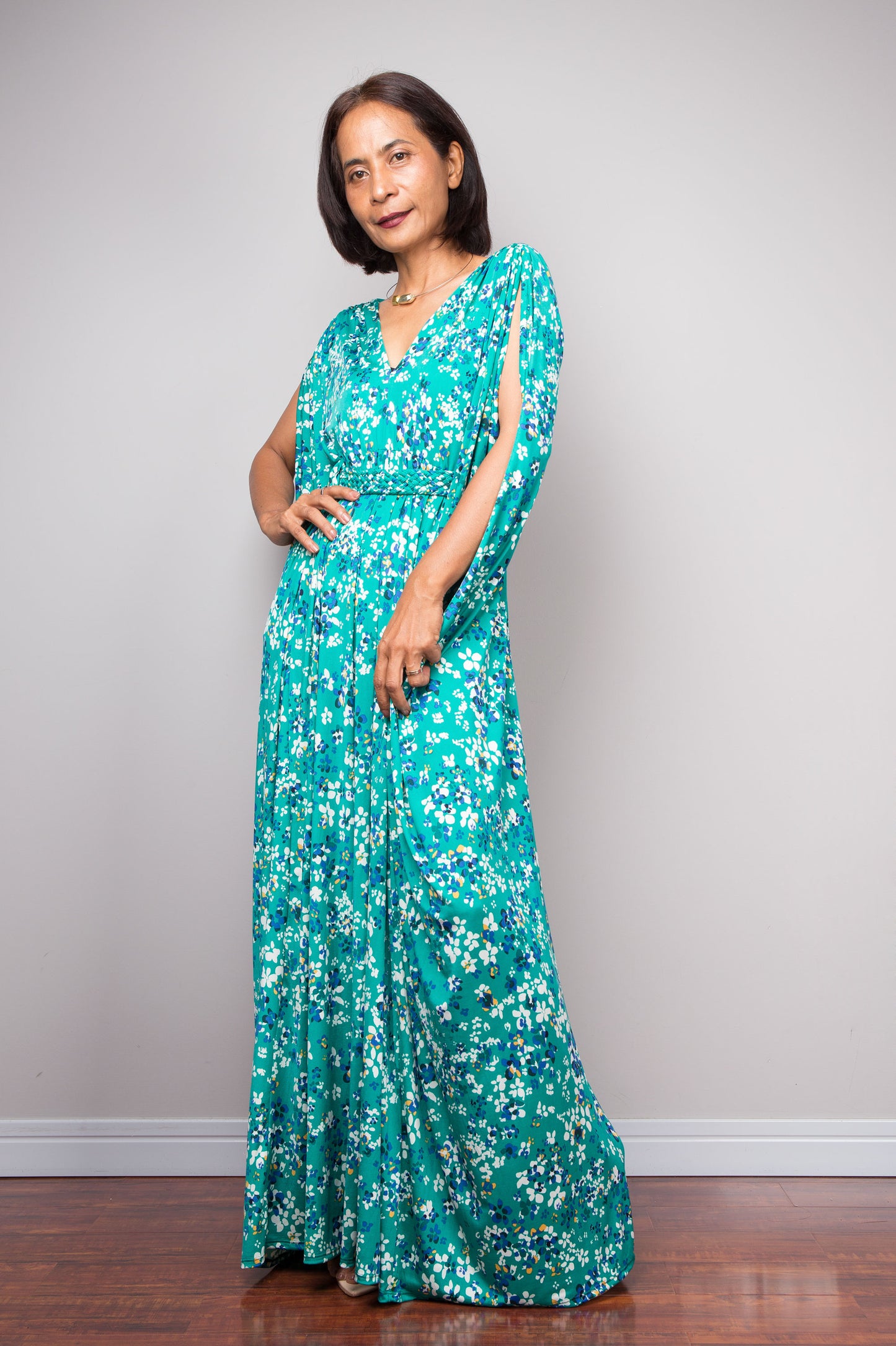 Petite woman wearing a teal green caftan dress against a plain background
