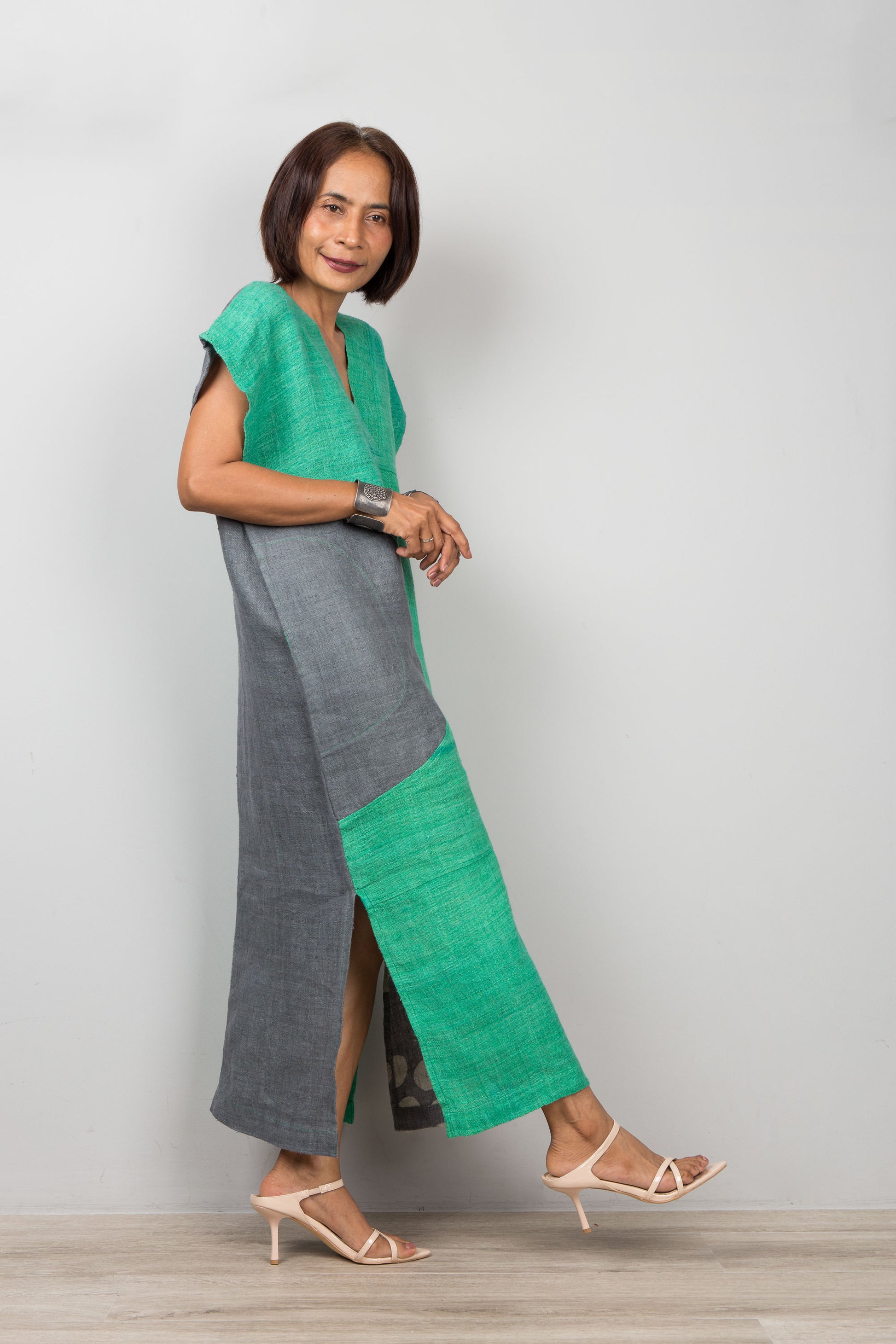 Woman wearing a green and gray hemp kaftan against a white background