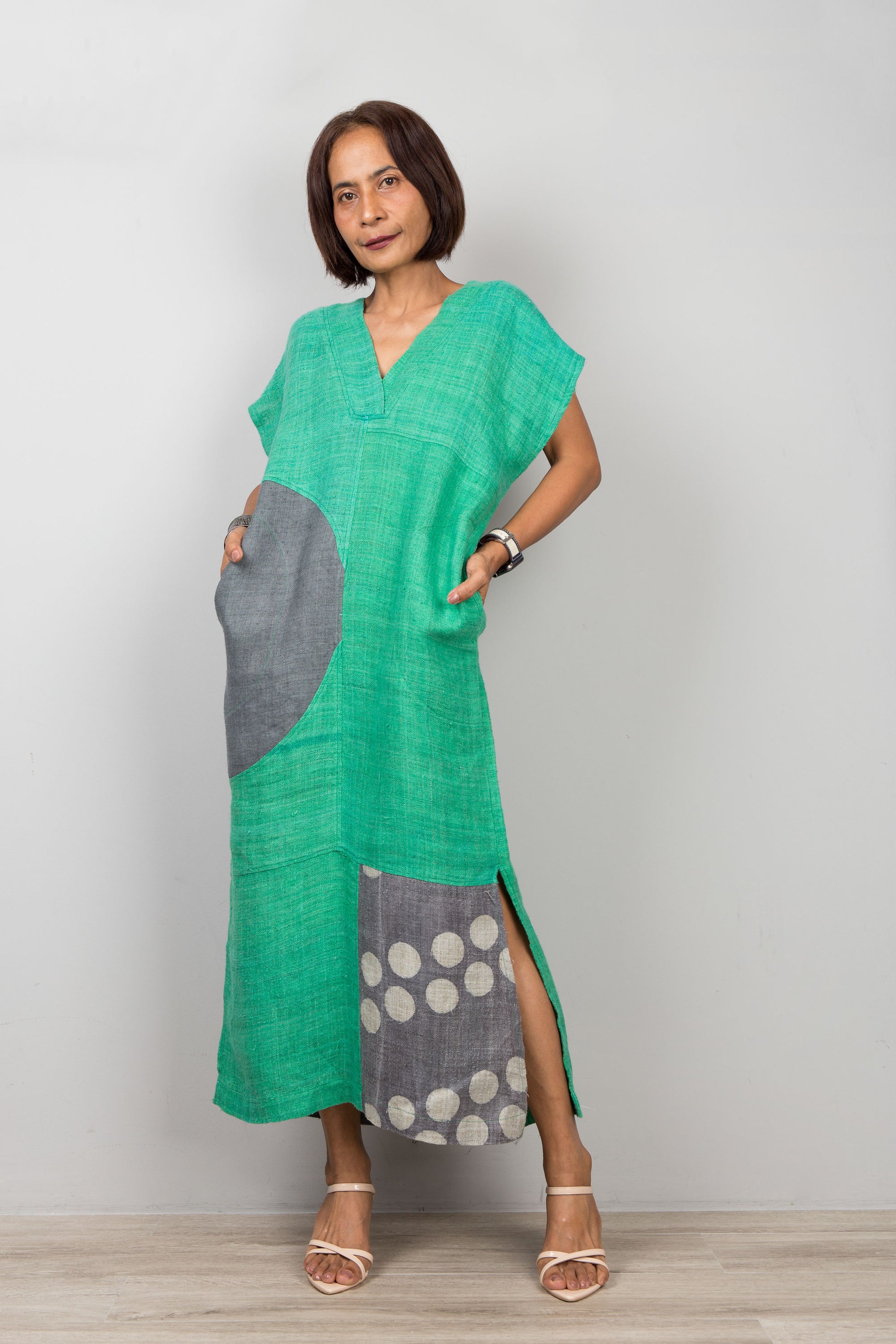 Woman wearing a green and gray patchwork dress with a white background