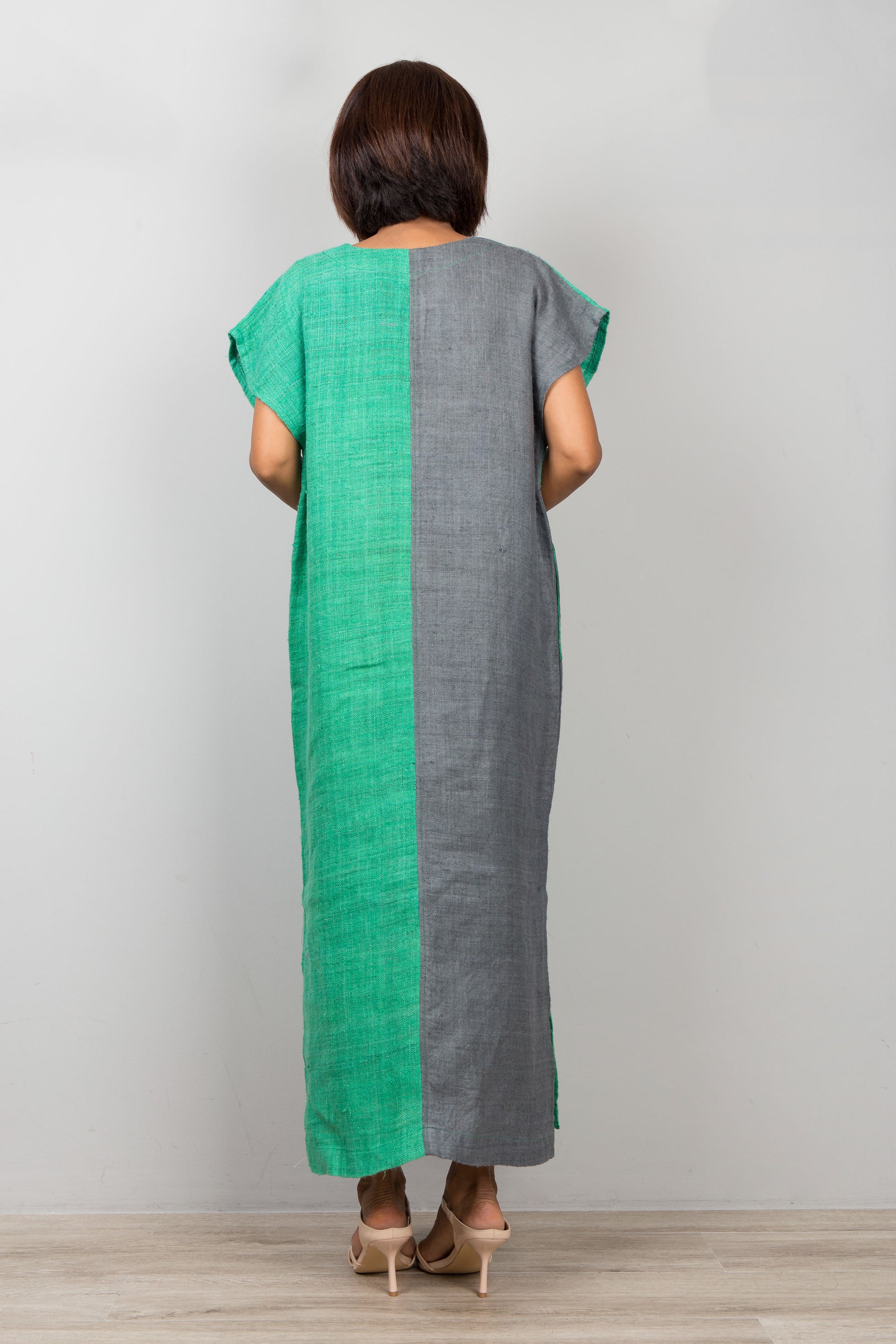 Woman wearing a green and gray dress against a plain background