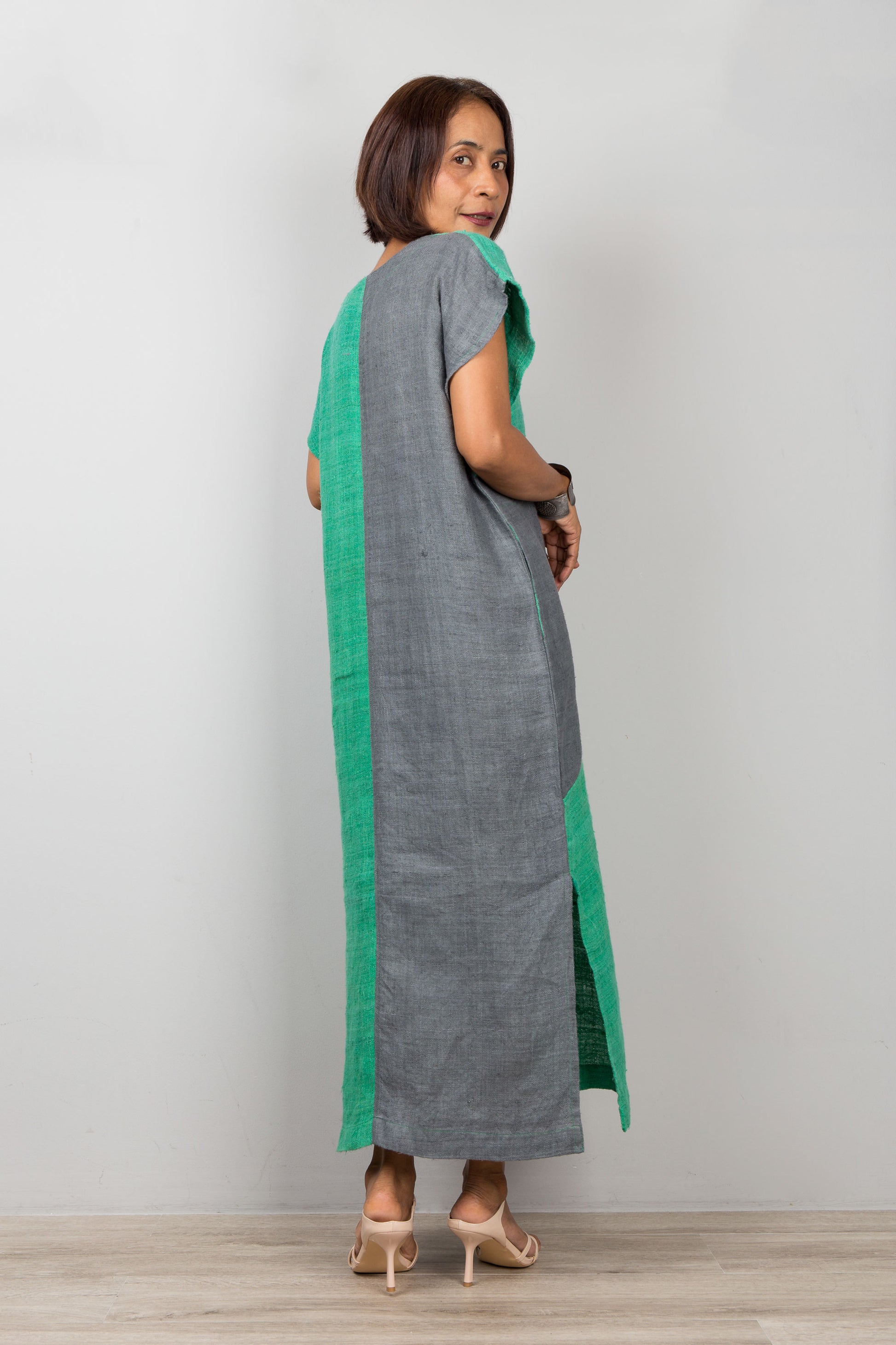 Woman wearing a gray dress with green accents on a plain background