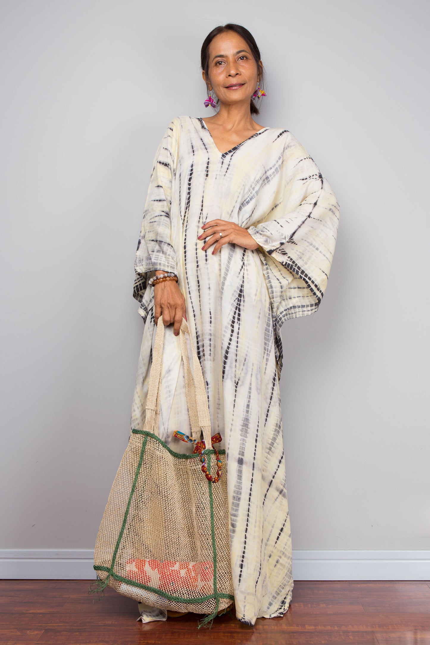 Woman wearing a tie dye kaftan dress with a plain background