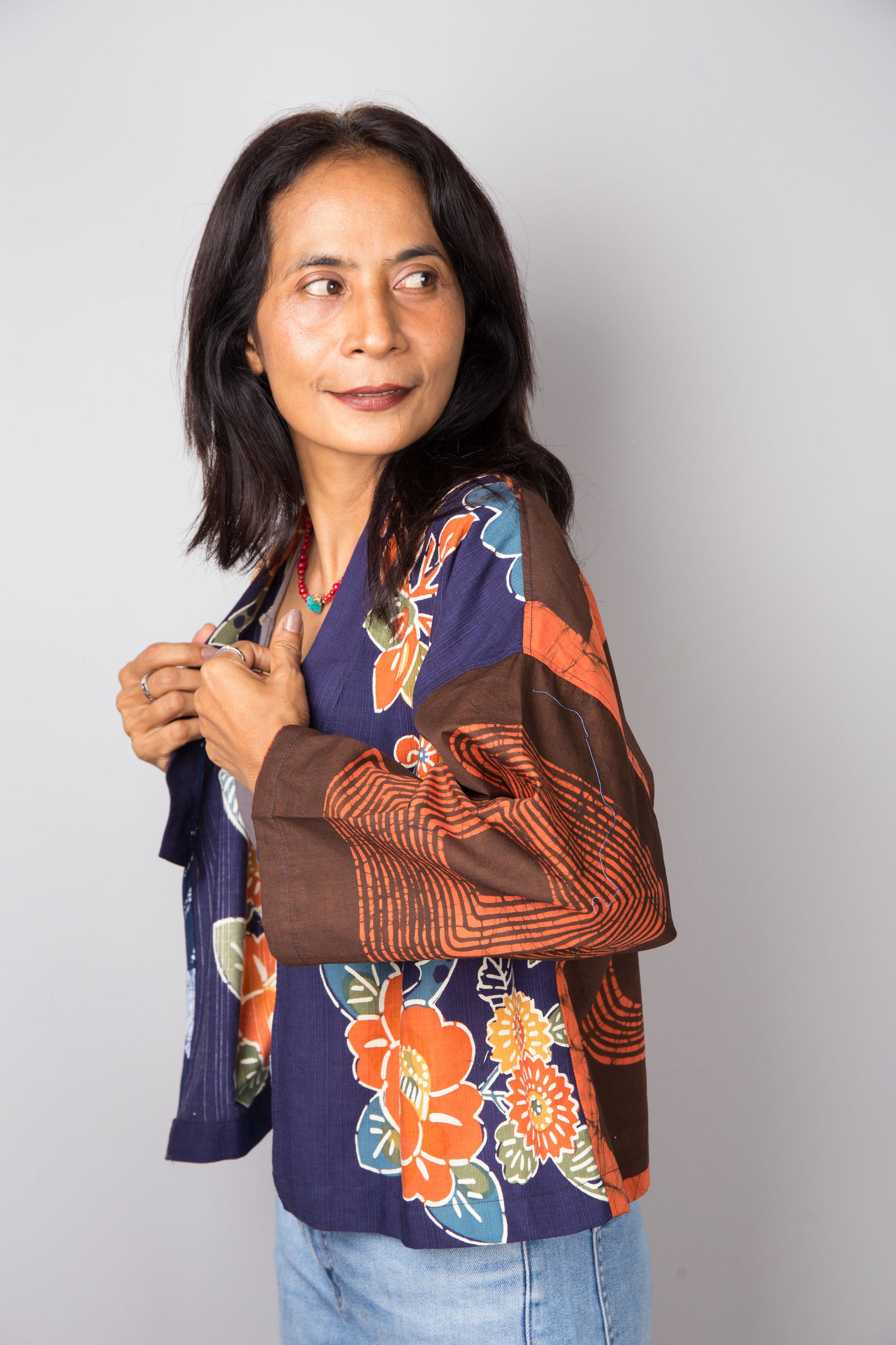Woman wearing a colorful cotton kimono jacket against a plain background