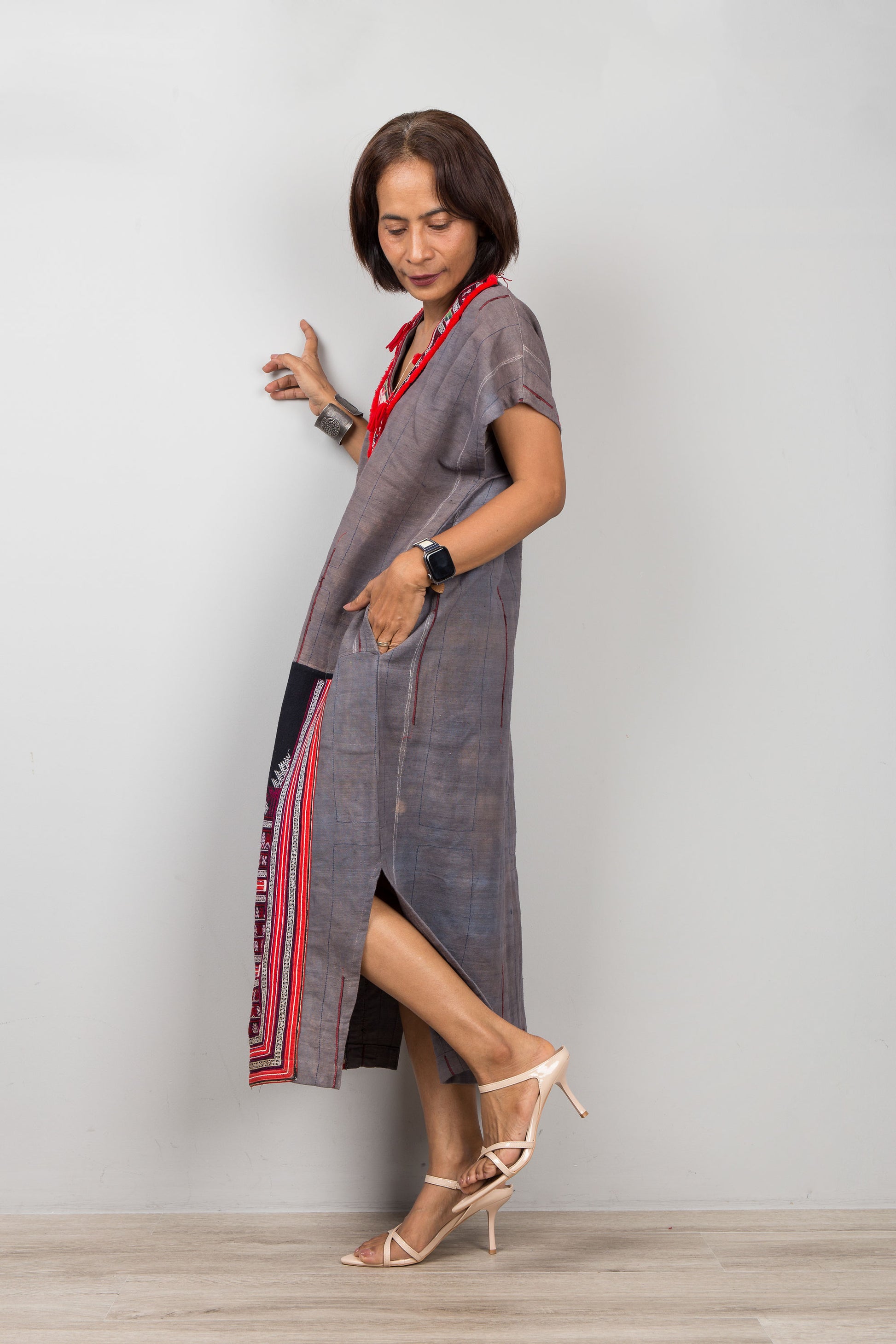 Woman wearing grey , short sleeve, caftan  dress with traditional embroidery on the bottom part of the dress