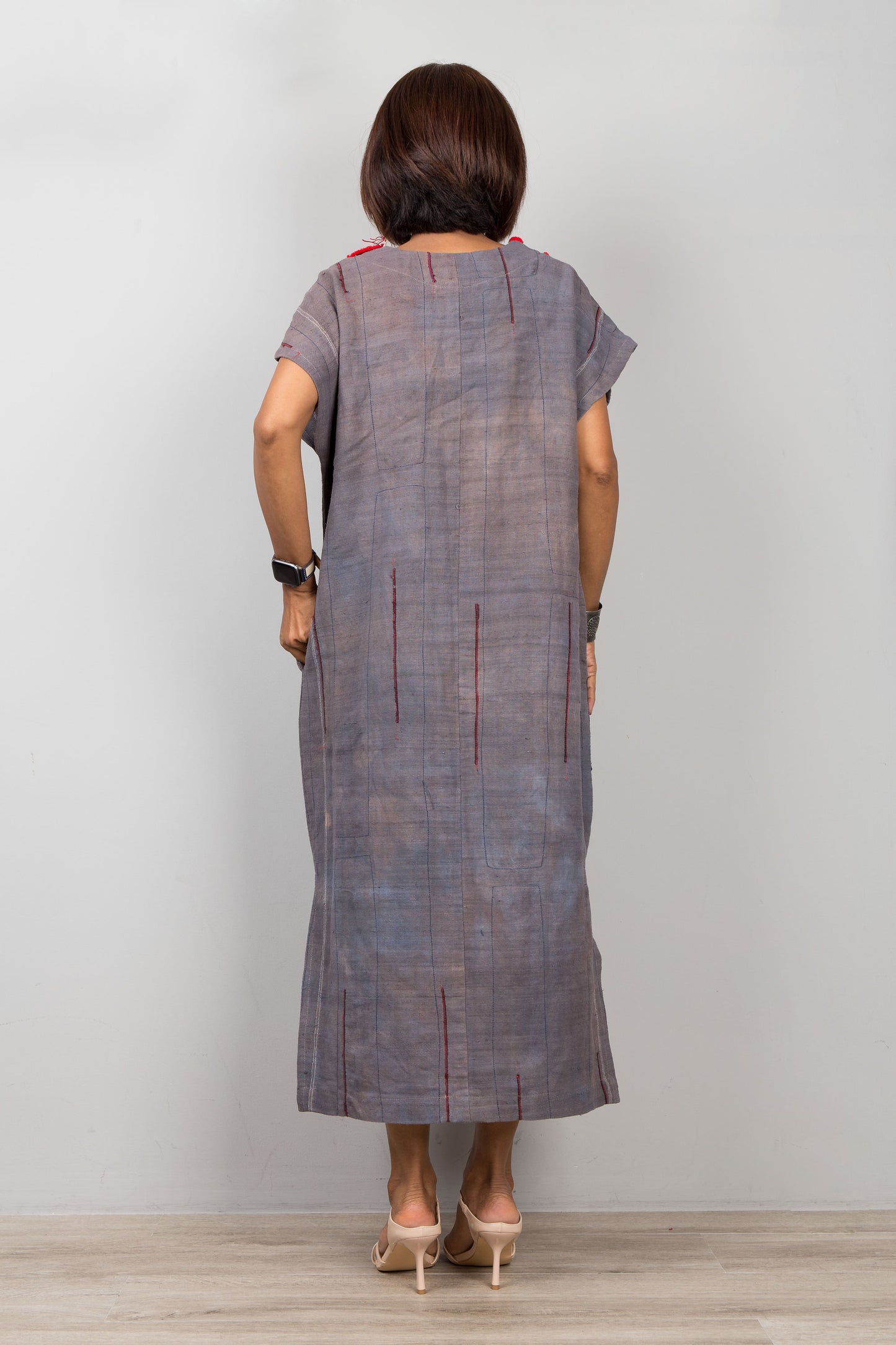 Woman wearing grey , short sleeve, dress  with side splits and with traditional embroidery on the bottom part of the kaftan