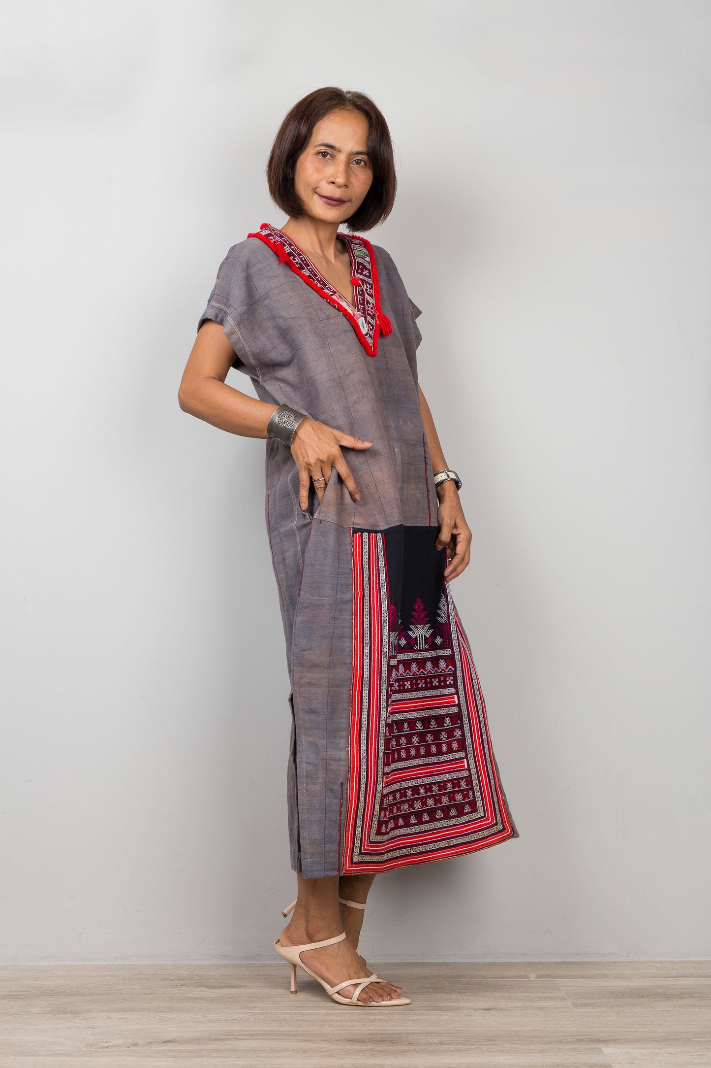 Woman wearing grey , short sleeve, dress with traditional embroidery on the bottom part of the kaftan dress
