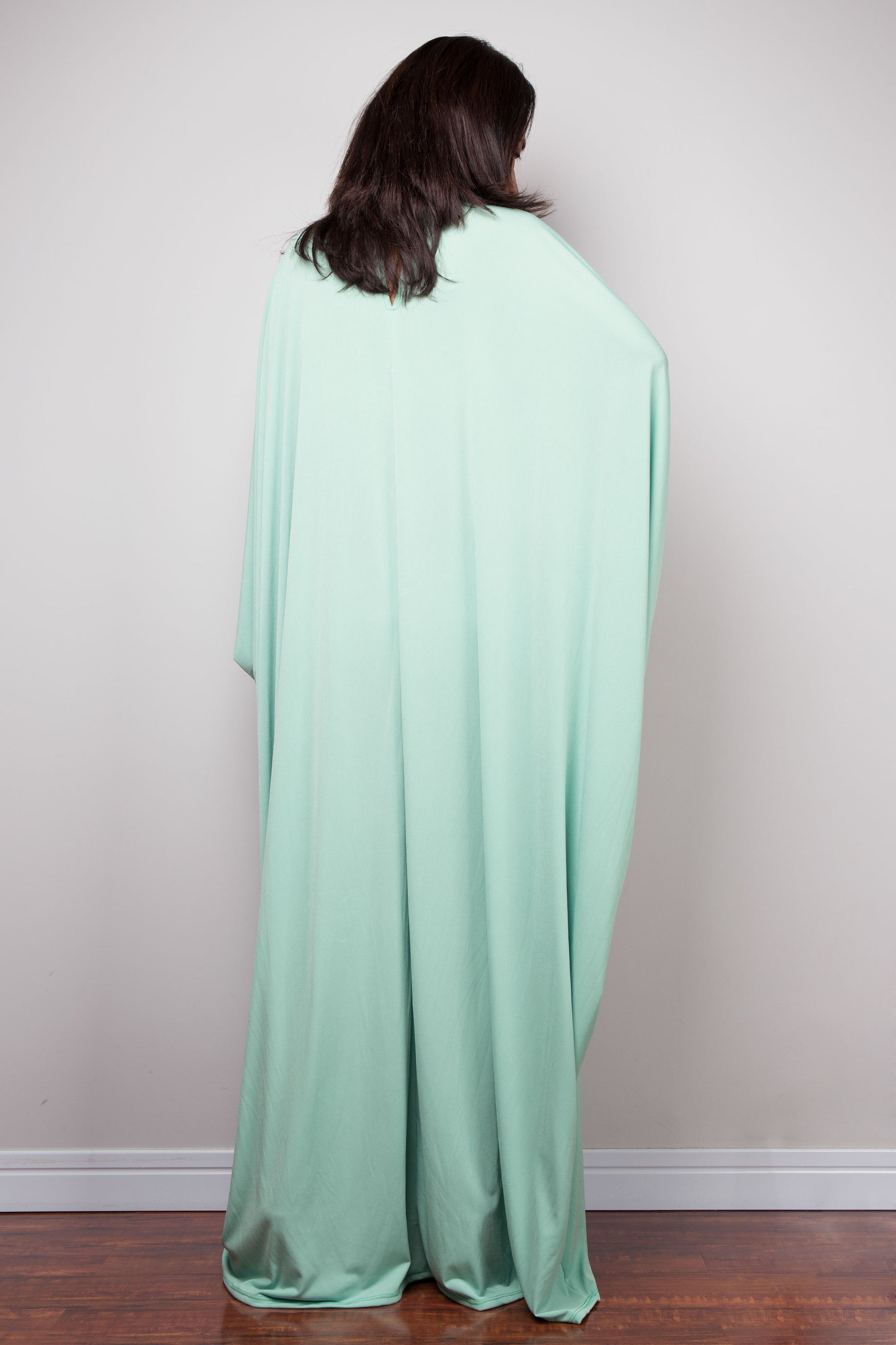 Person wearing a light green kaftan dress against a plain background