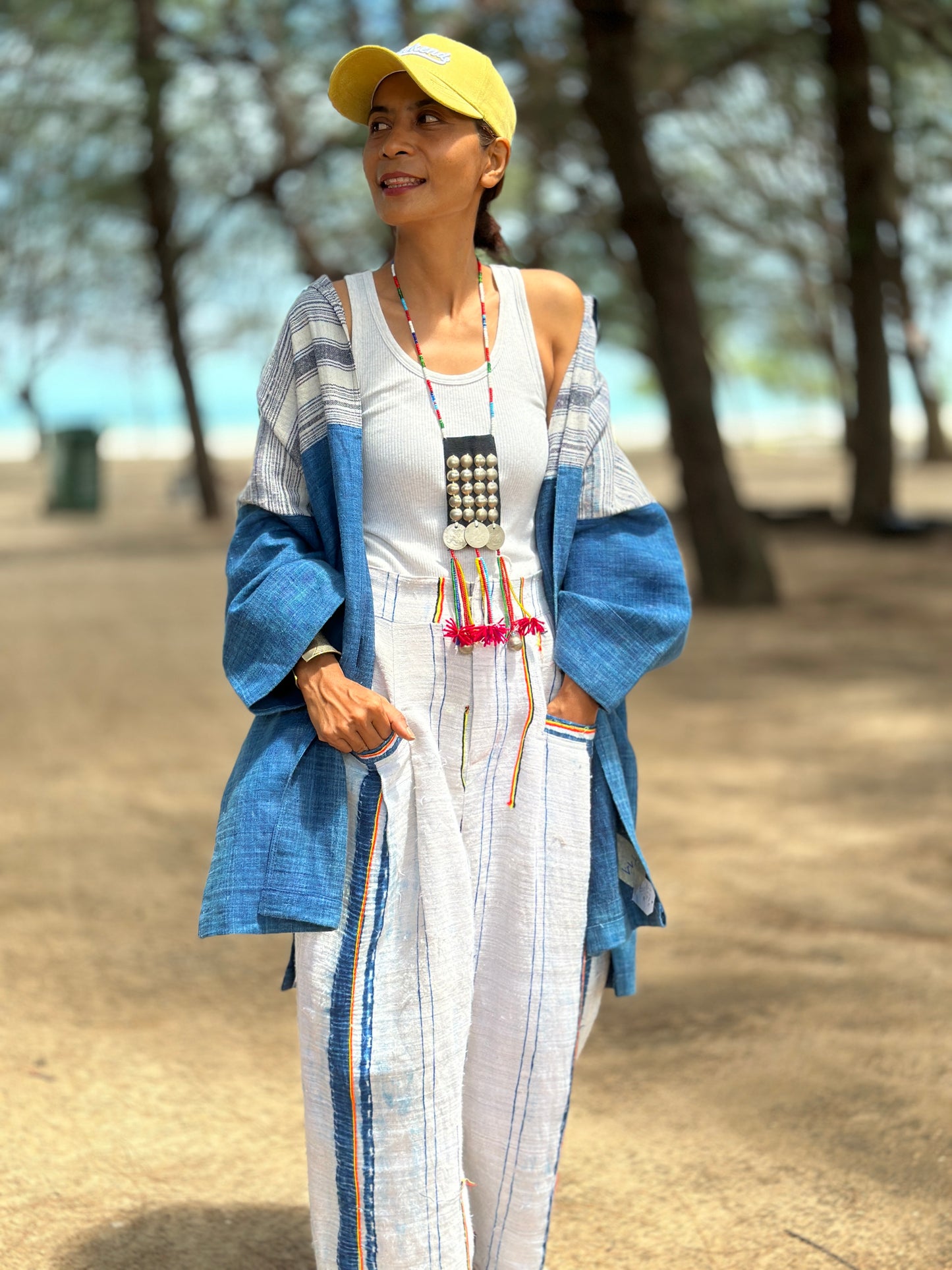 Woman wearing natural indigo hill tribe open front cardigan outdoors at the beach, sleeve raised, Nuichan