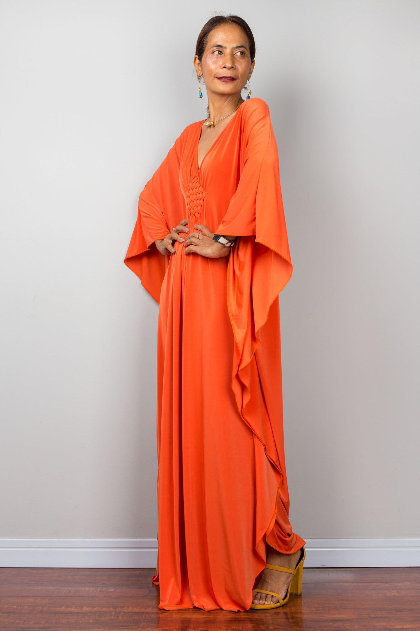 Orange kaftan dress with batwing sleeves and plunging v neckline. Side view
