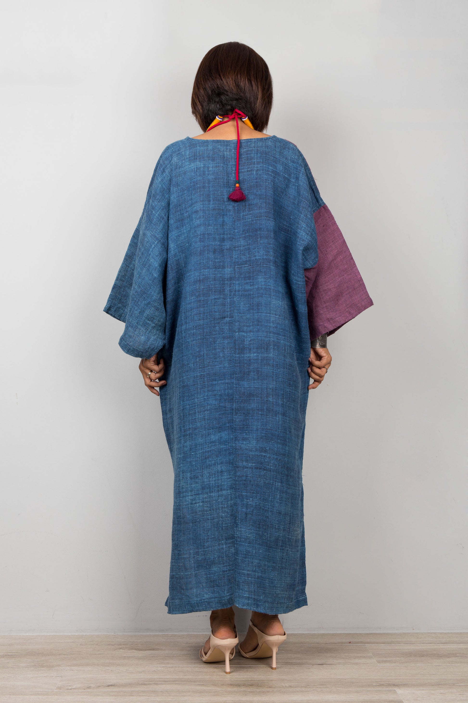 Person wearing a blue and purple dress with a plain background
