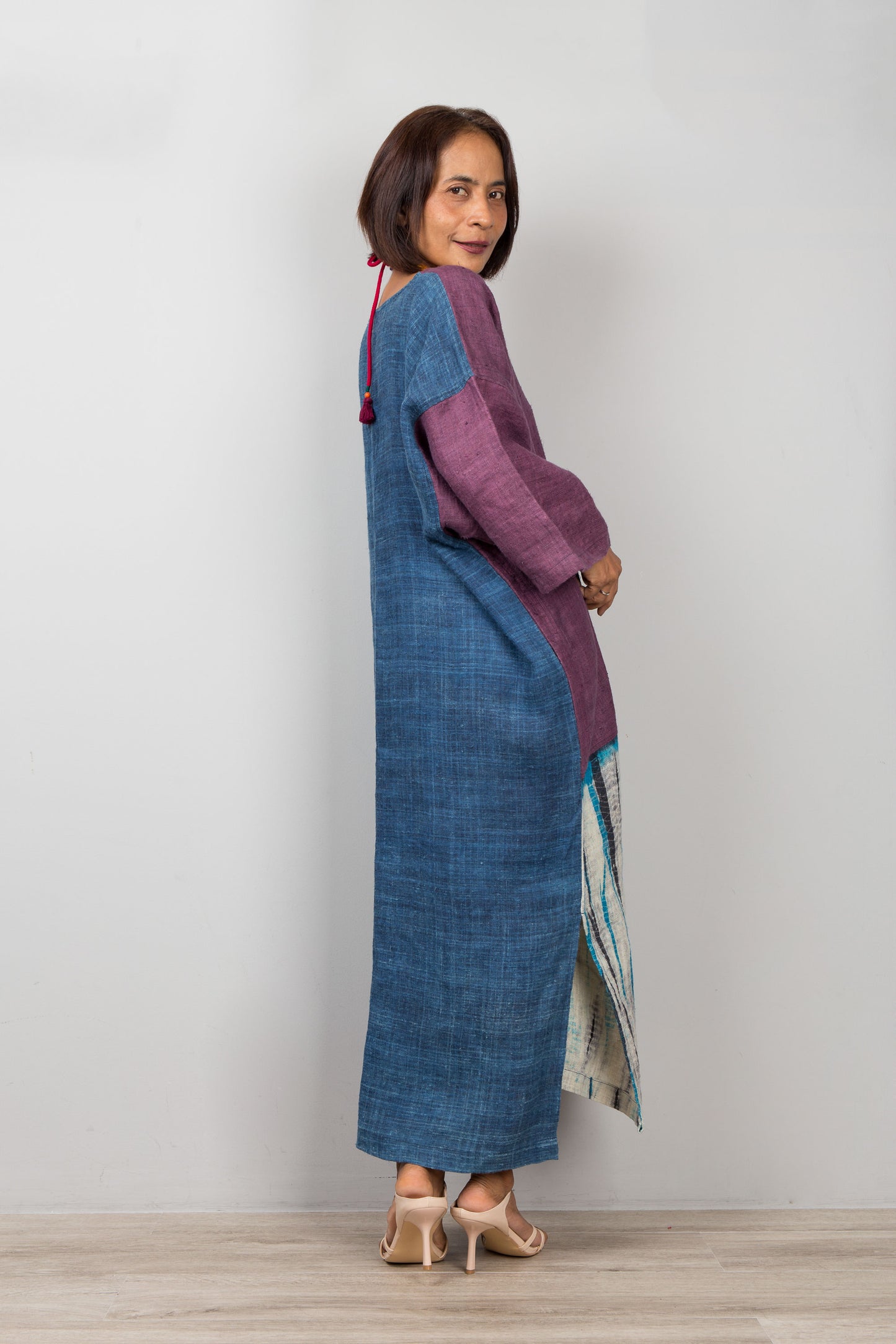 Woman wearing a long, patterned dress with a blue and purple design against a plain background