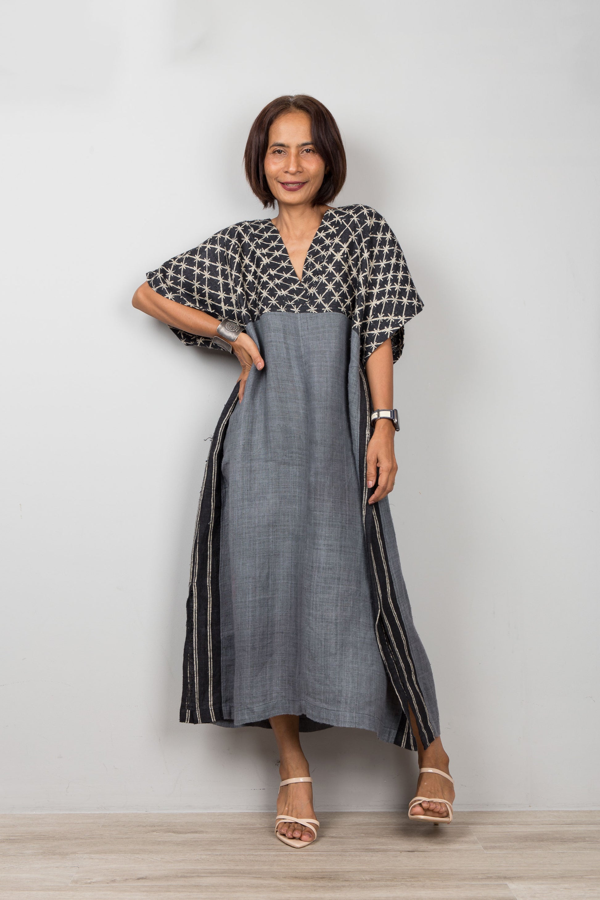 Woman wearing a gray petite caftan in handwoven hemp, standing against plain background