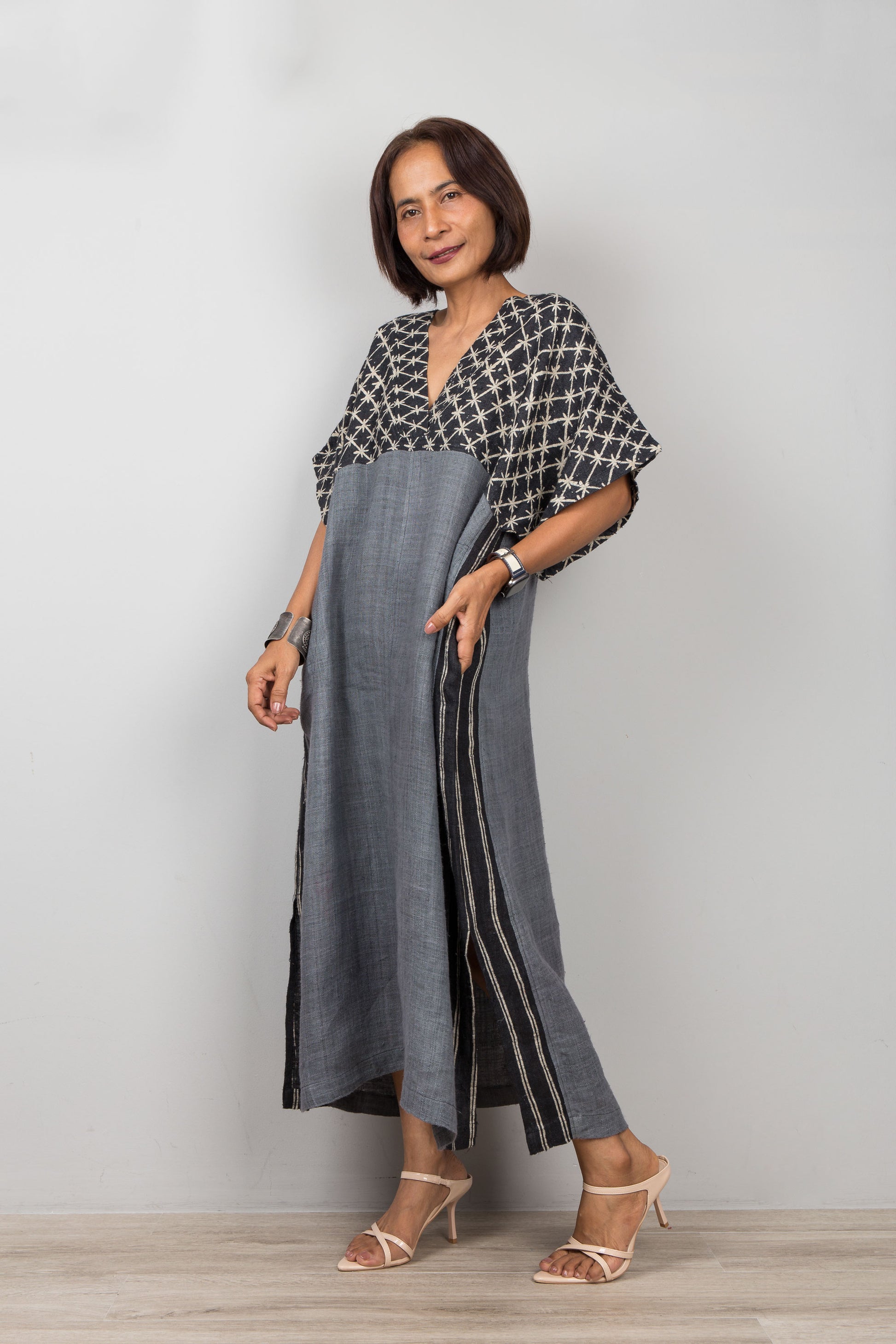 Woman wearing a gray petite caftan dress on a plain background
