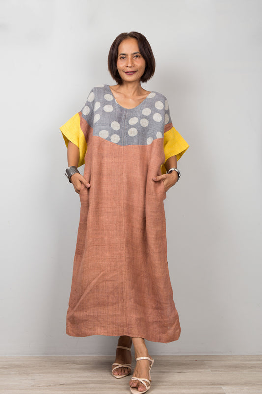 Woman wearing a dress with a polka dot top and brown skirt part on a plain background