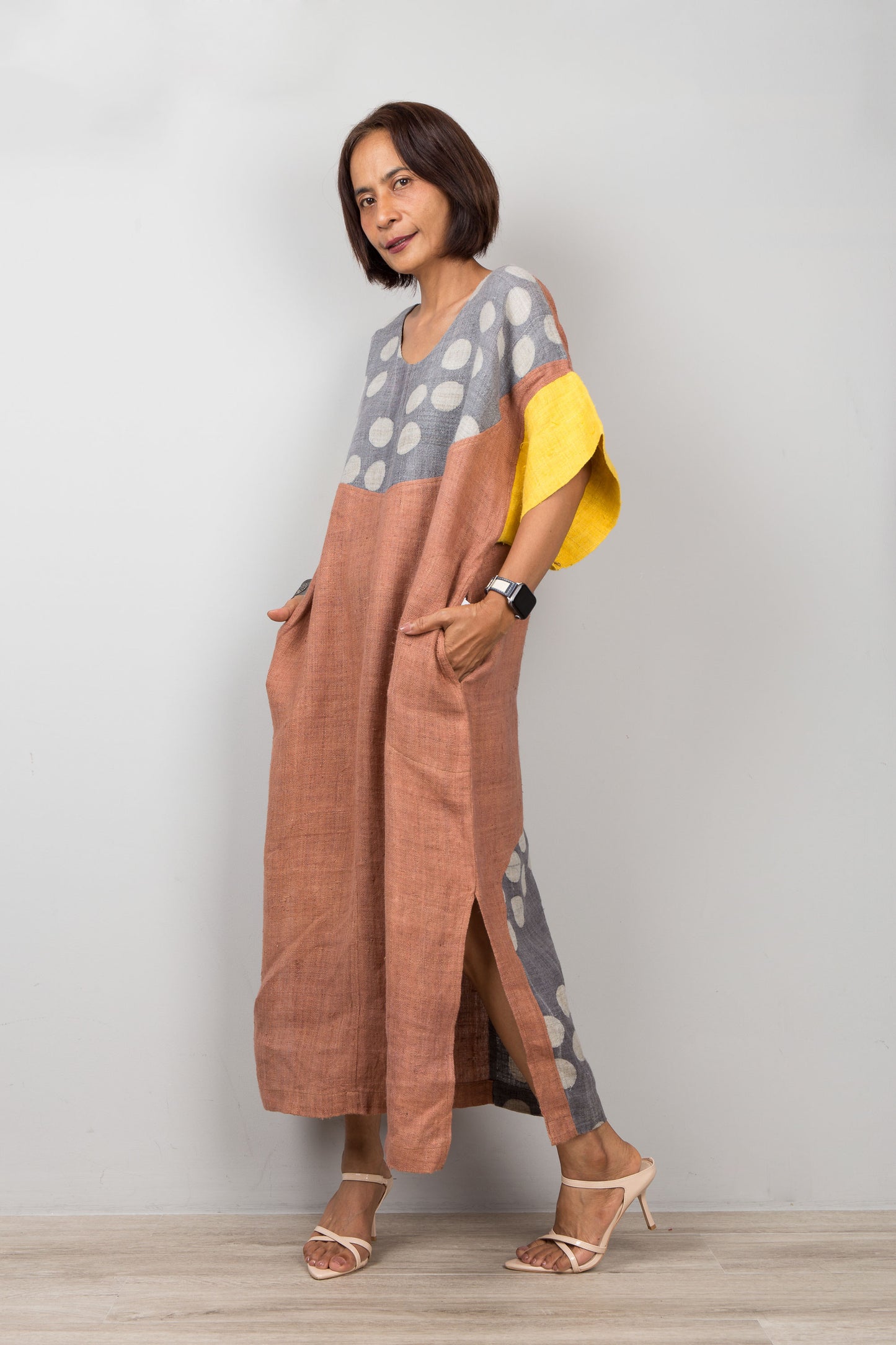 Woman wearing a long, patterned hemp kaftan dress for petite, with a plain background