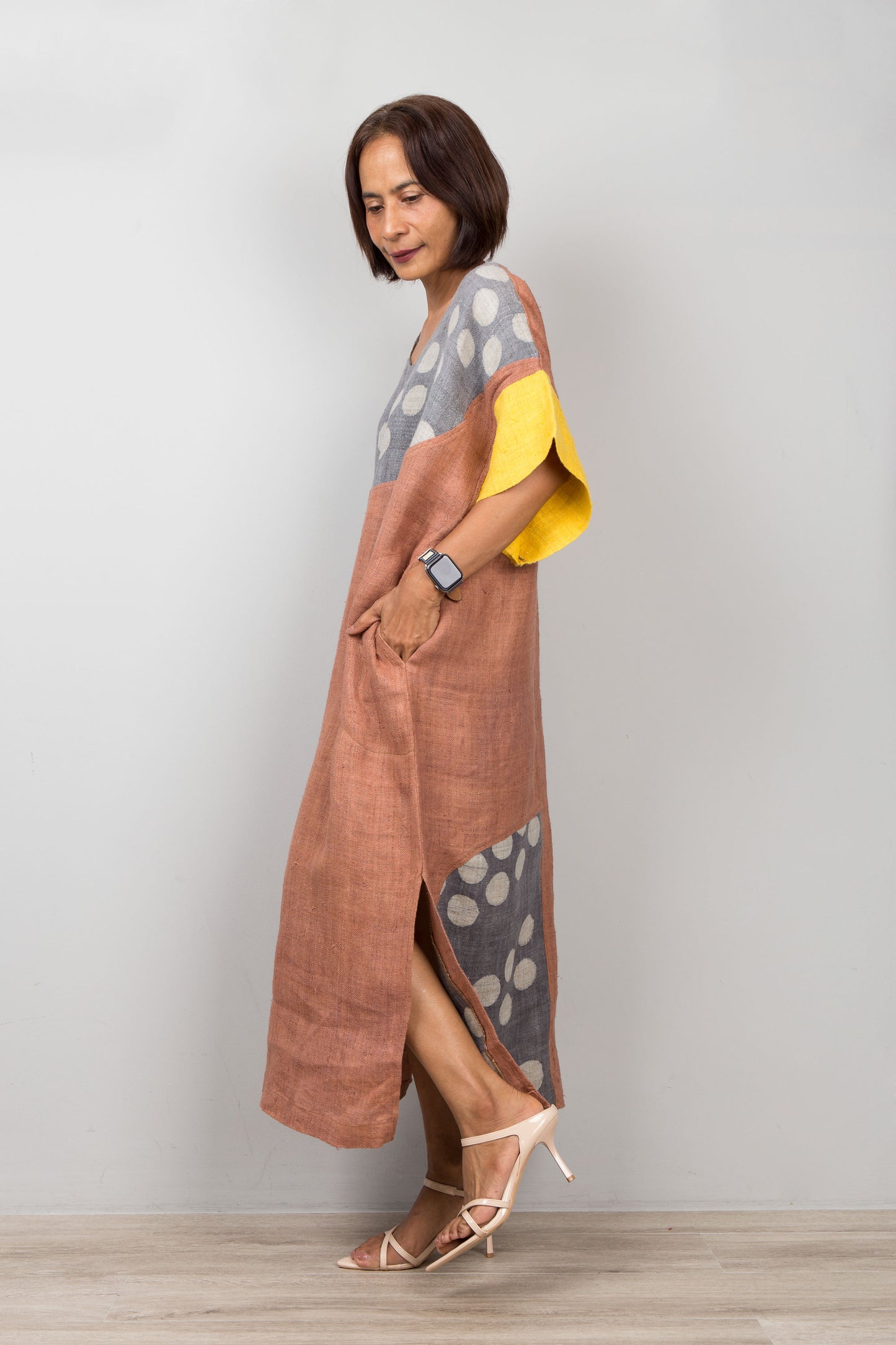 Woman wearing a colorful petite kaftan dress with a patterned design against a plain background