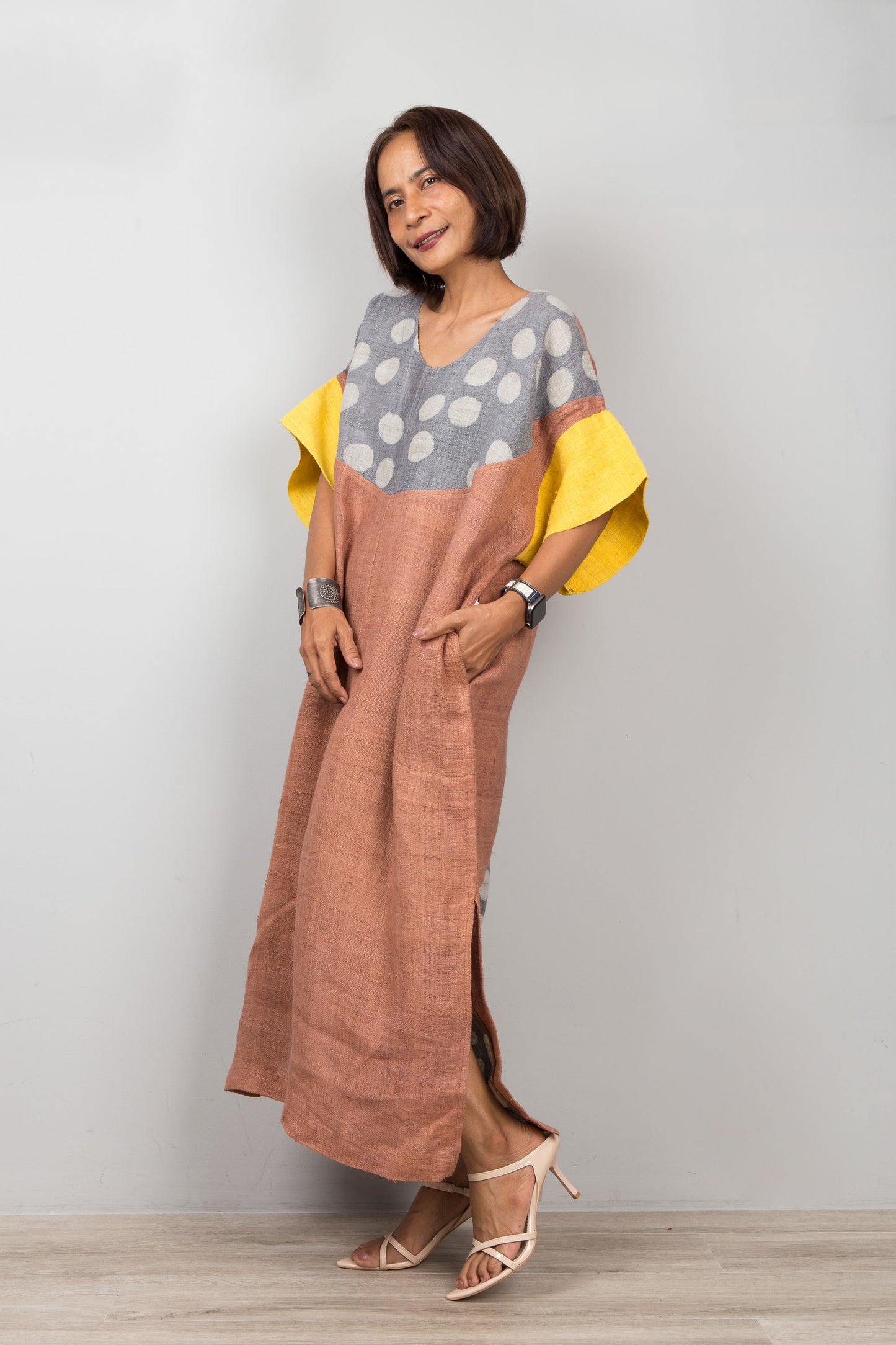 Woman wearing a colorful outfit with a polka dot top and brown pants on a plain background