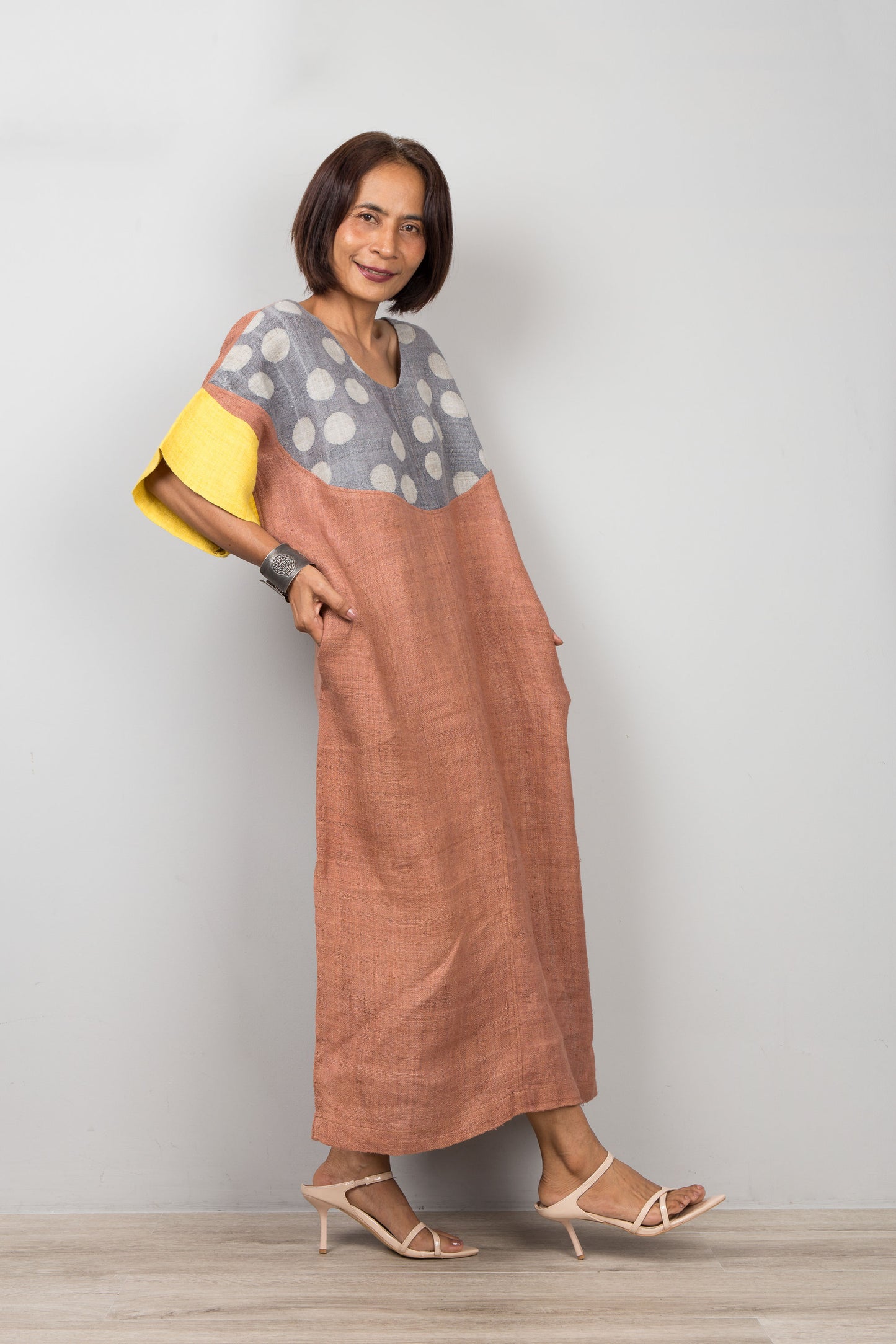 Woman wearing a long, two-tone petite caftan dress with a polka dot top and solid skirt against a plain background.