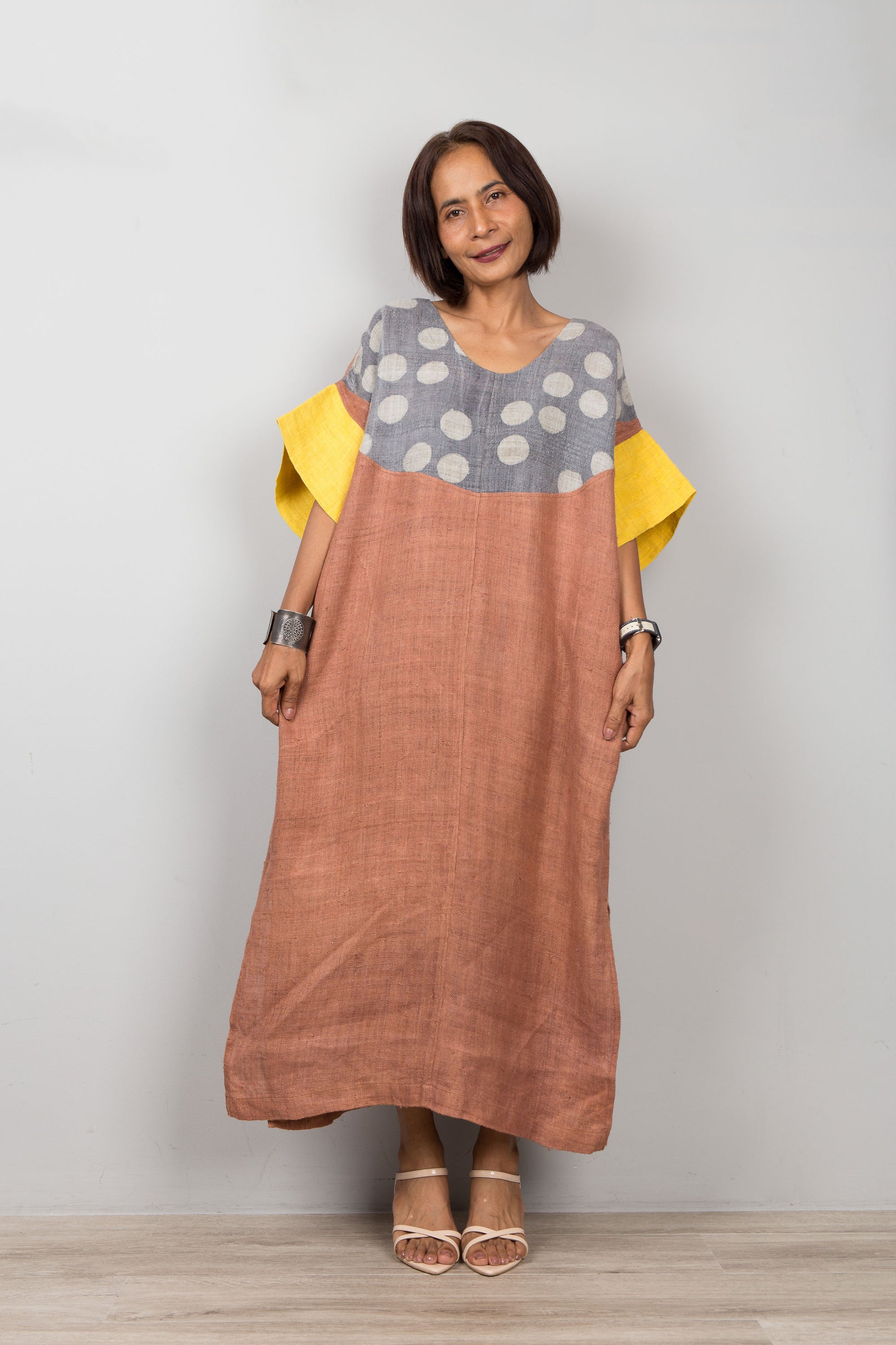 Woman wearing a long, two-tone petite kaftan dress with a polka dot pattern on a plain background