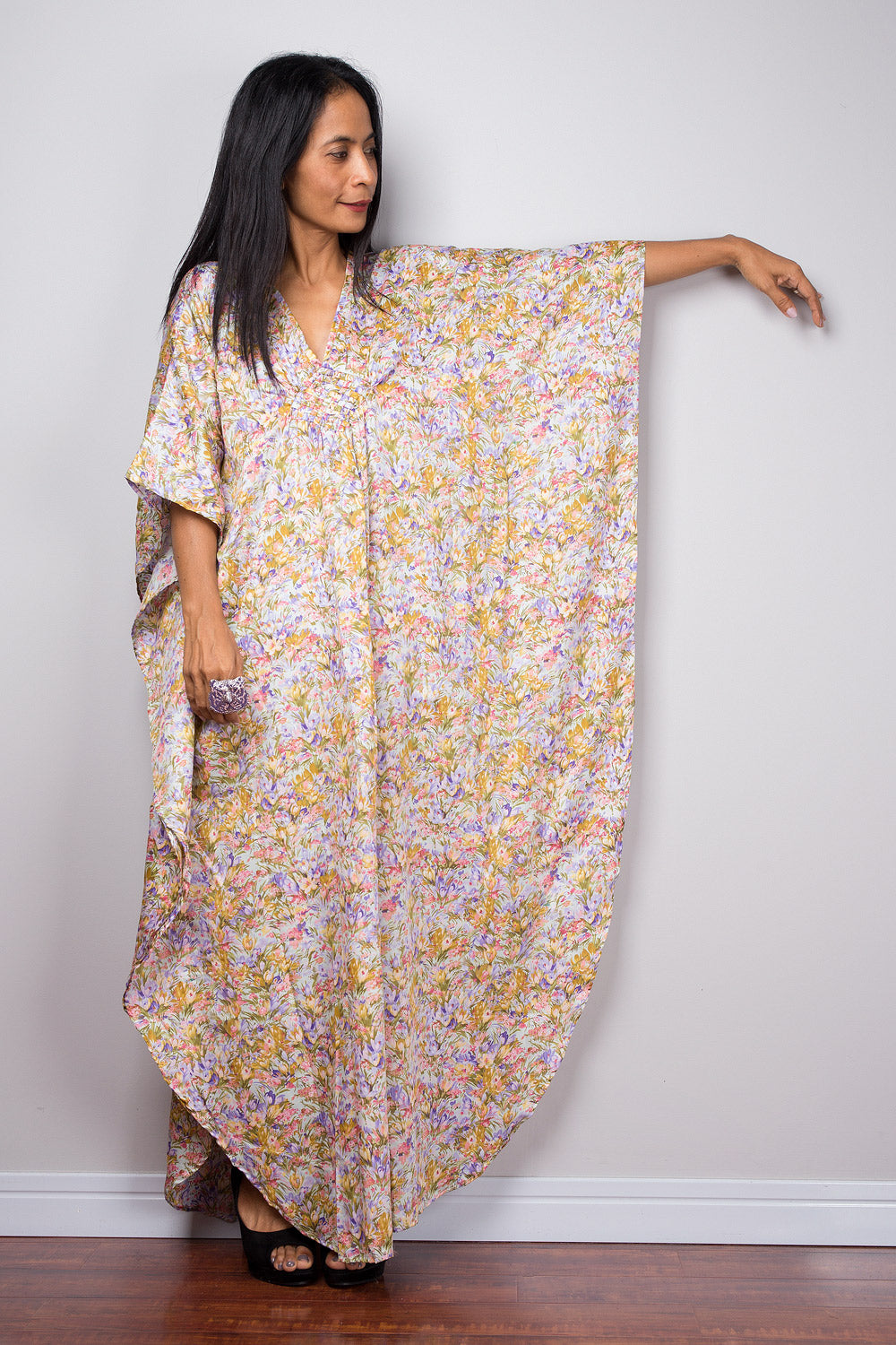 Woman wearing a floral kaftan dress against a plain background