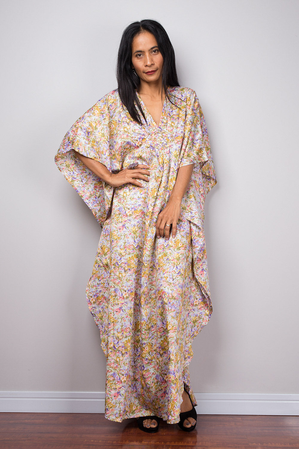 Petite woman wearing a floral dress against a plain background