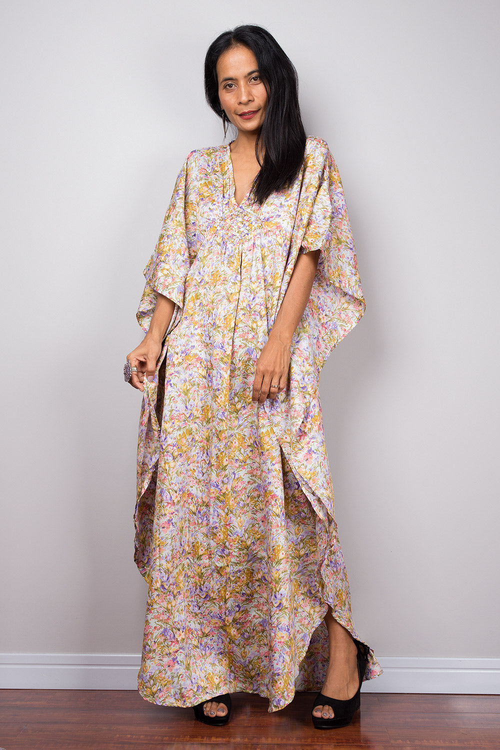 Woman wearing a petite floral kaftan dress standing against a plain background