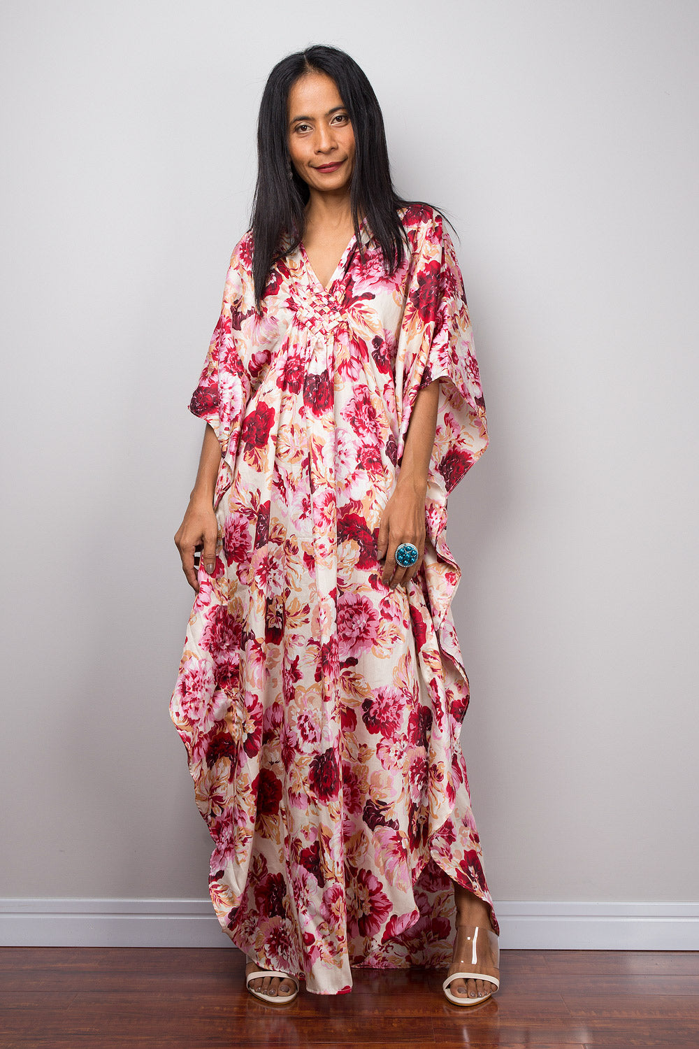 Petite woman wearing a pink floral caftan dress against a plain background