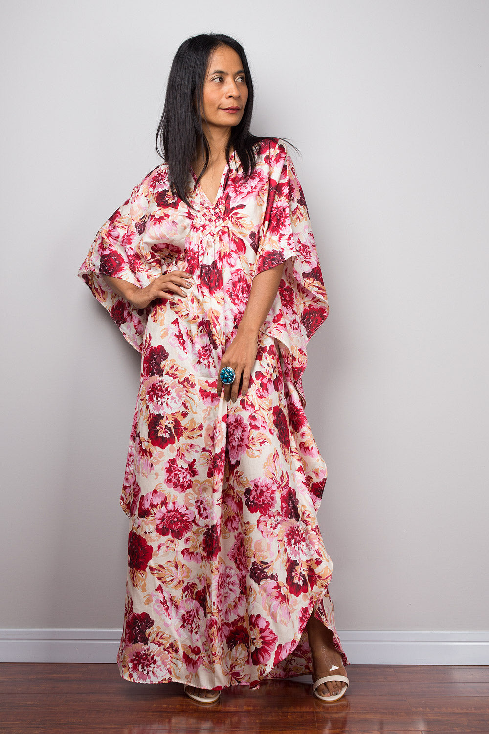 Petite Woman wearing a pink floral caftan dress against a plain background