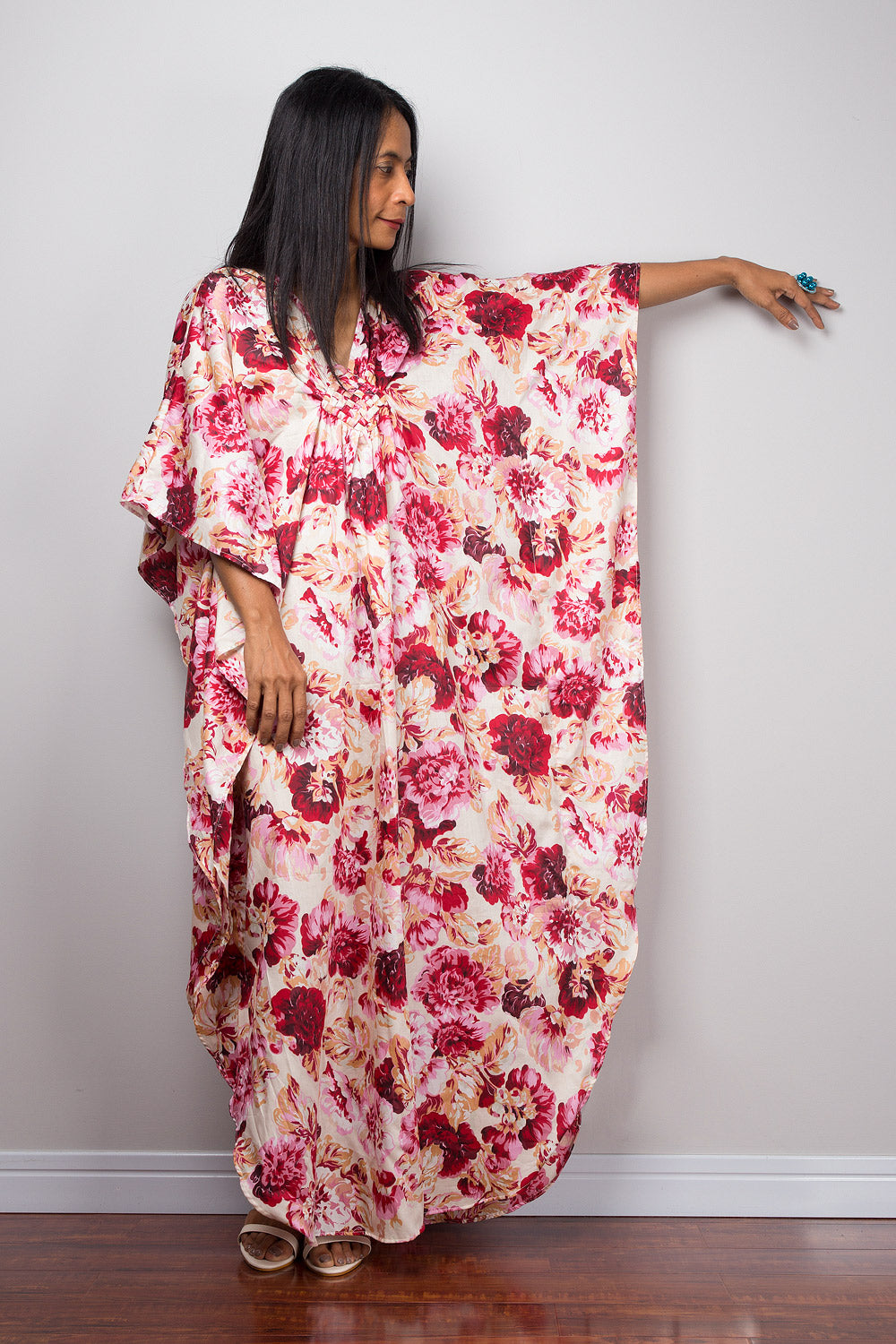 Petite woman wearing a pink floral caftan with a plain background