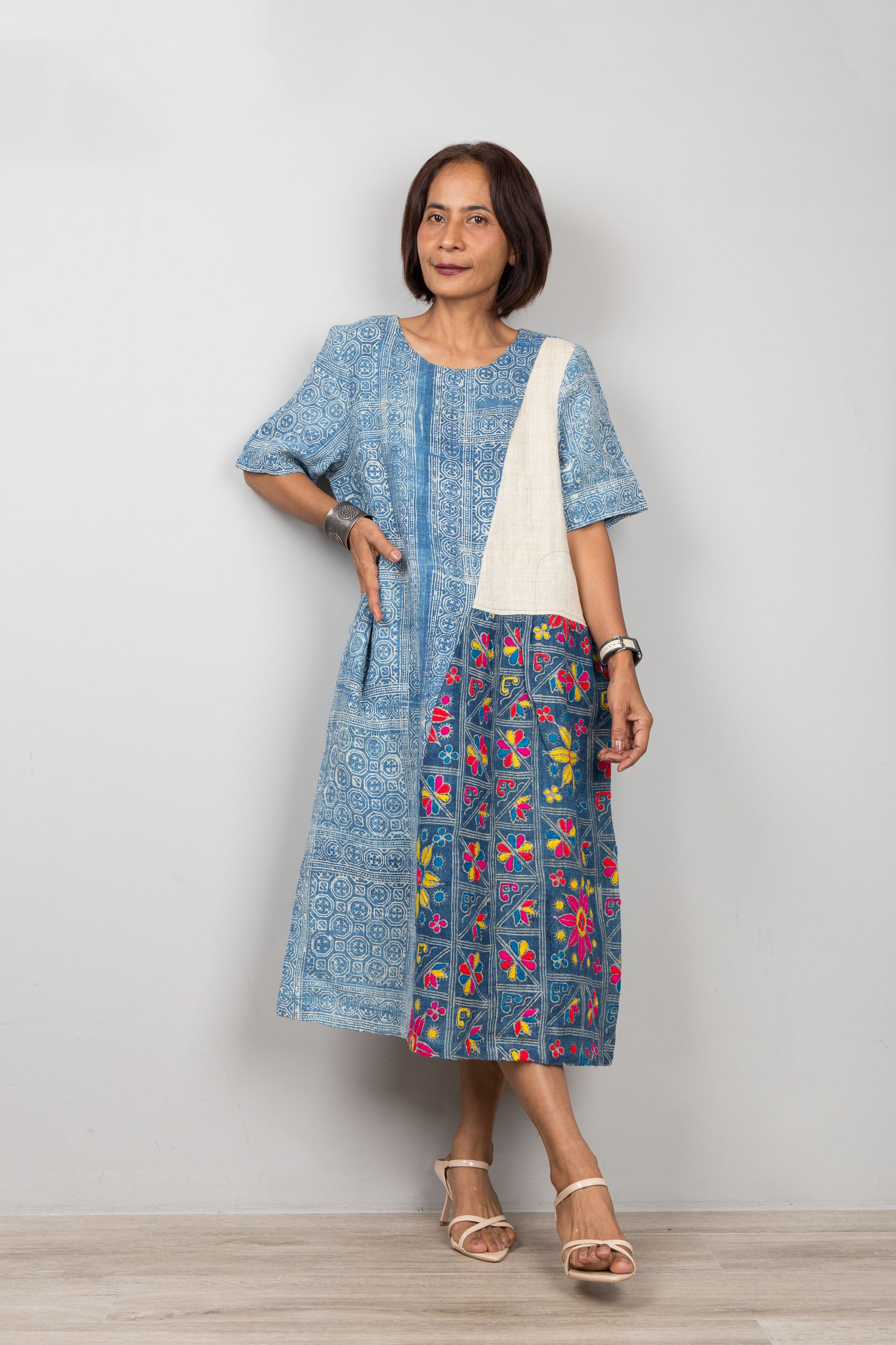 Nuichan wearing a batik hemp dress with floral embroidery against a plain background