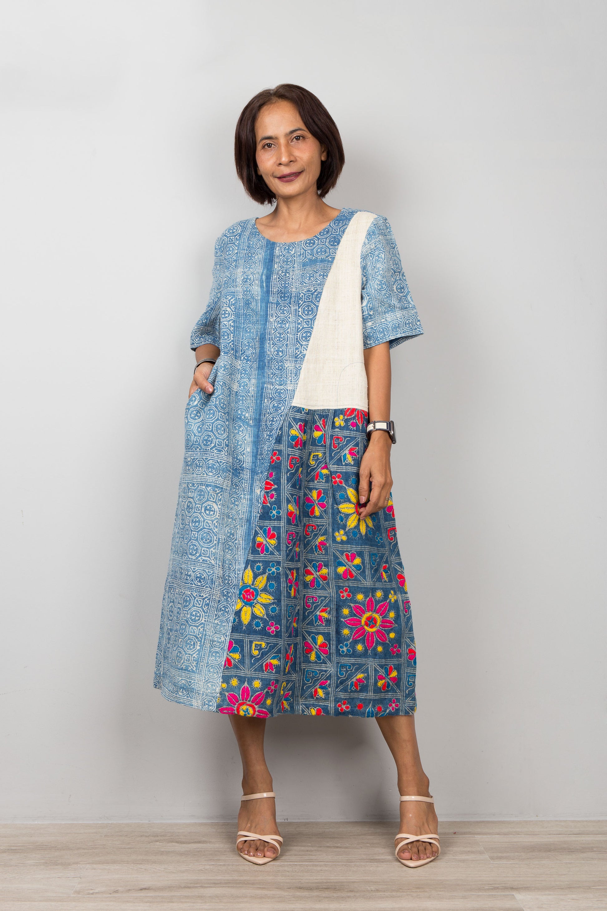 Nuichan wearing a blue batik hemp kaftan dress with floral embroidery against a plain background
