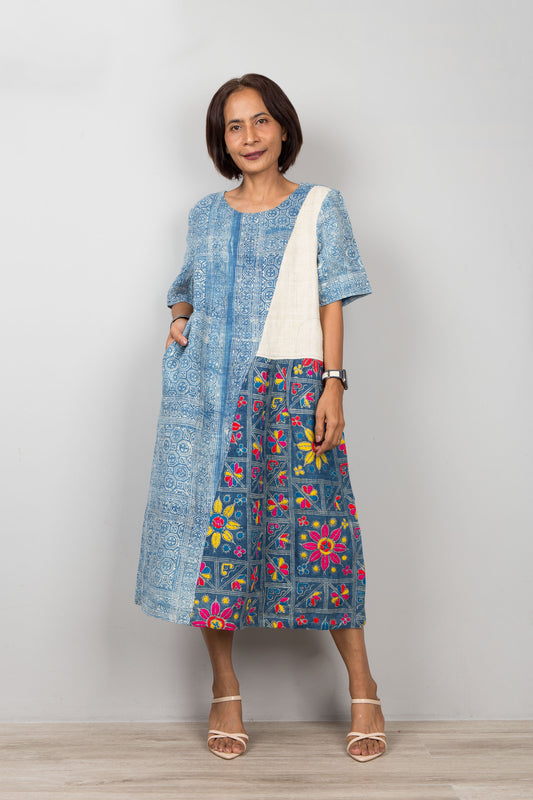 Nuichan wearing a blue batik hemp kaftan dress with floral embroidery against a plain background