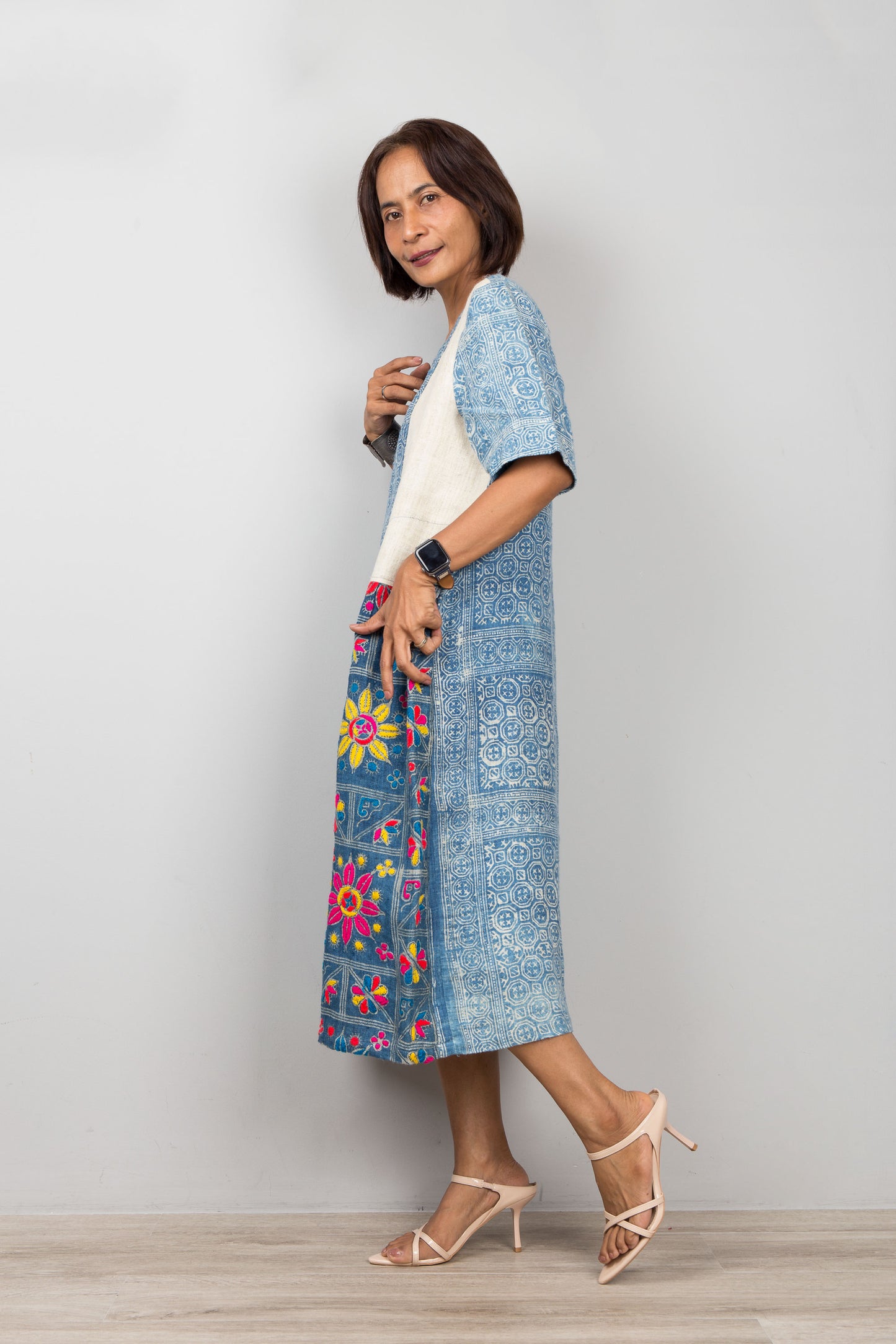 Nuichan wearing a blue batik caftan dress with floral embroidery against a plain background
