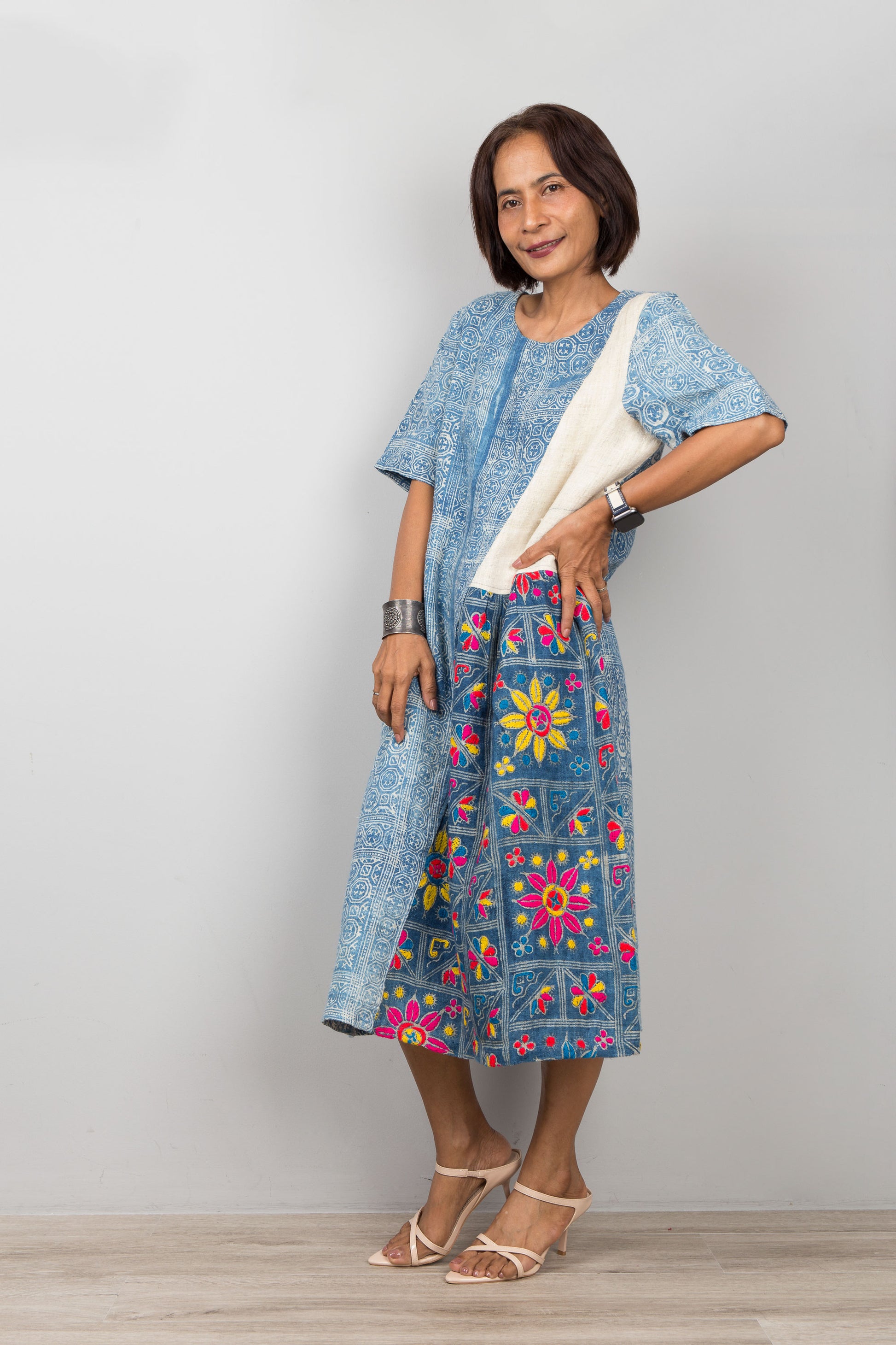 Nuichan wearing a batik indigo hemp kaftan dress with floral embroidery against a plain background