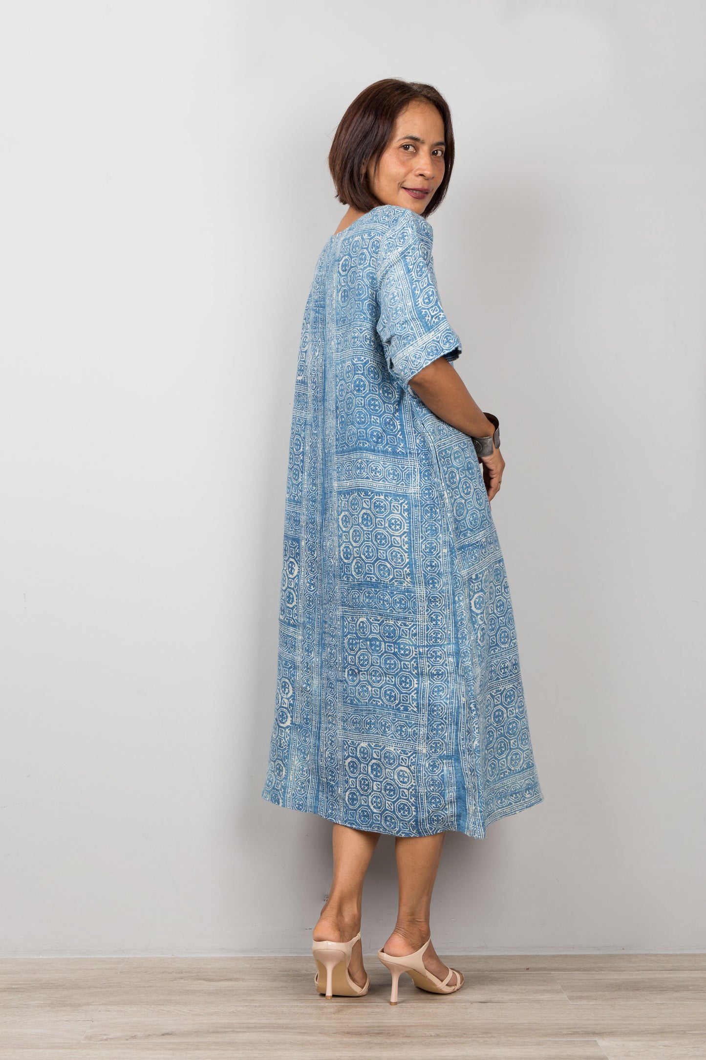 Nuichan wearing an indigo blue batik petite kaftan dress with floral embroidery against a plain background