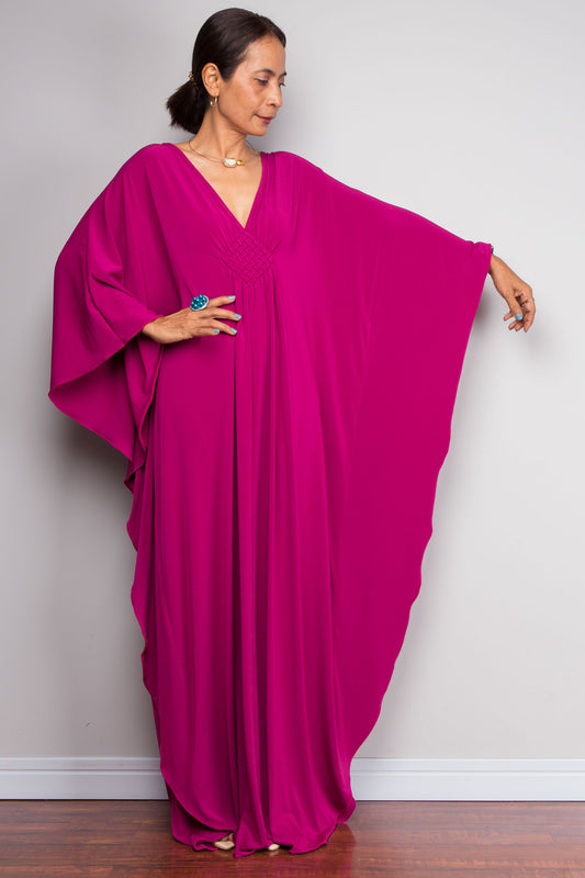 Woman wearing a vibrant pink caftan against a plain background