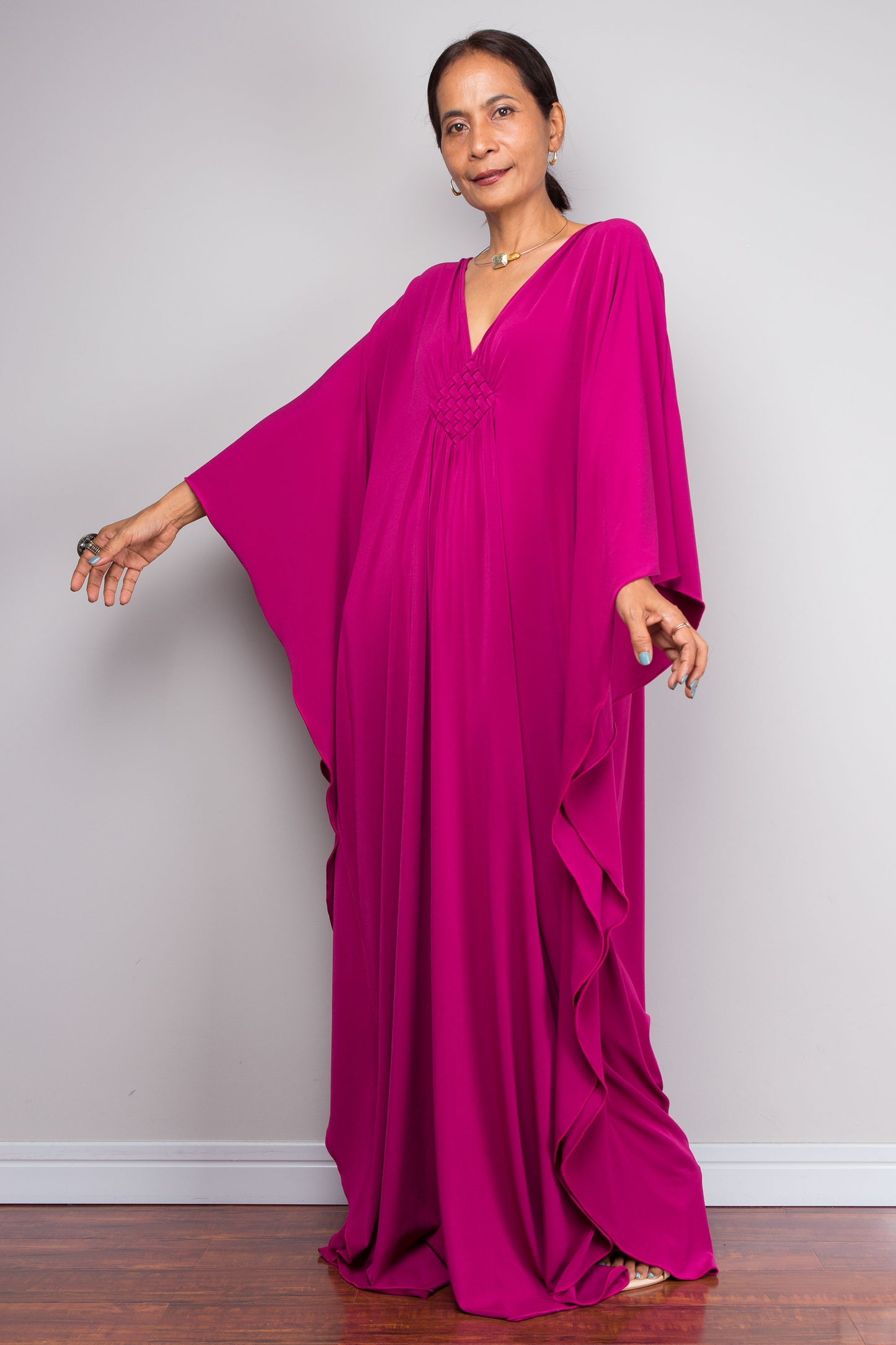 Woman wearing a vibrant pink kaftan against a plain background