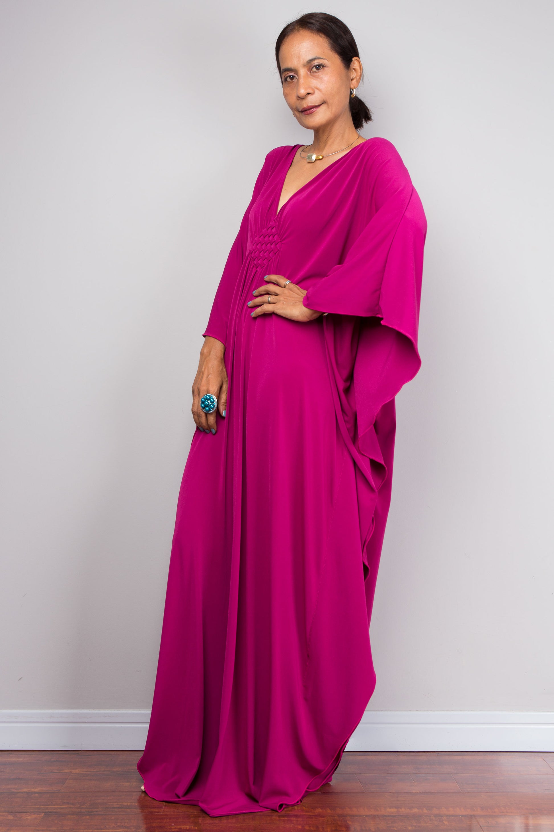 Woman wearing a vivid pink kaftan against a plain background
