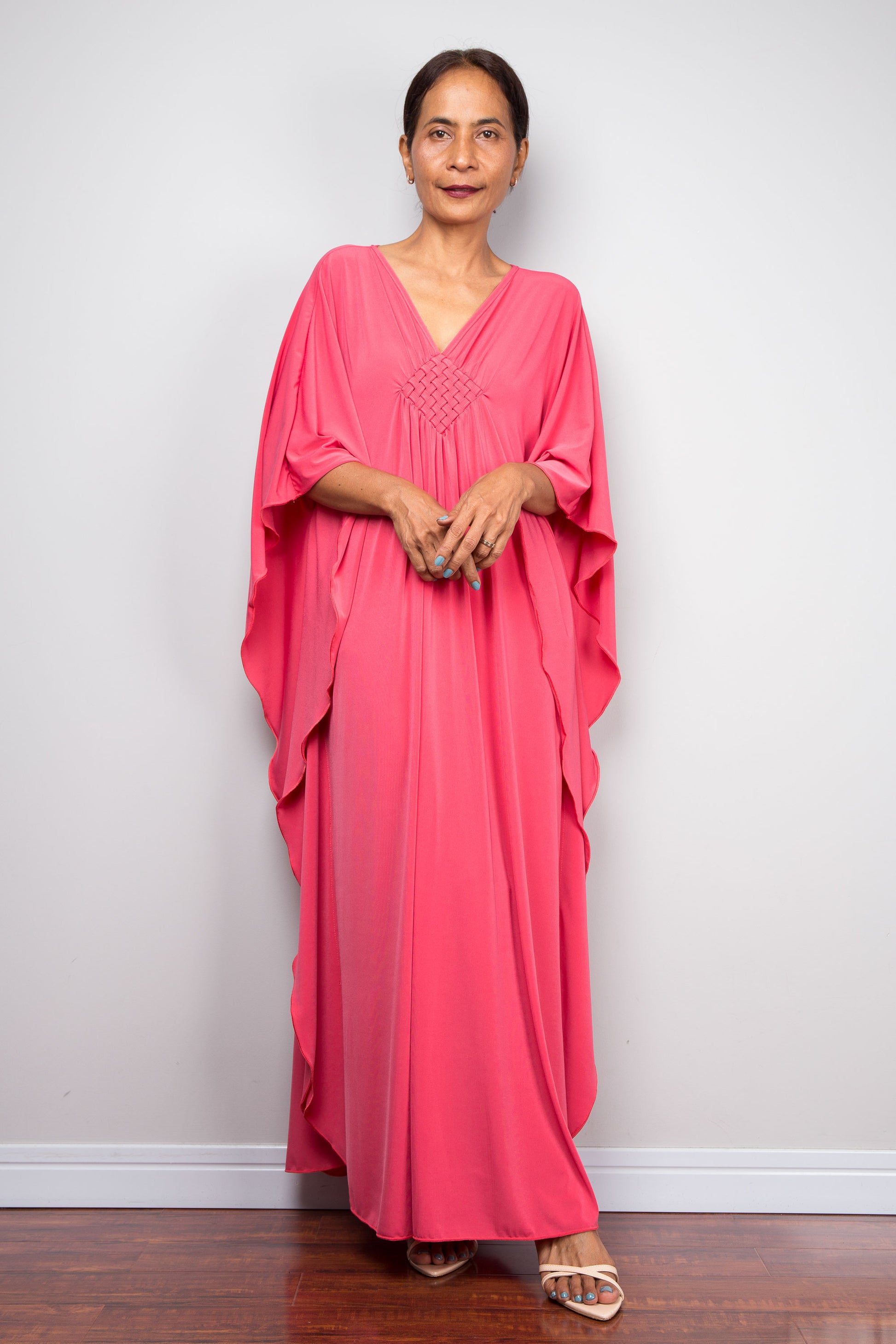 Petite Woman wearing a pink caftan dress against a plain background