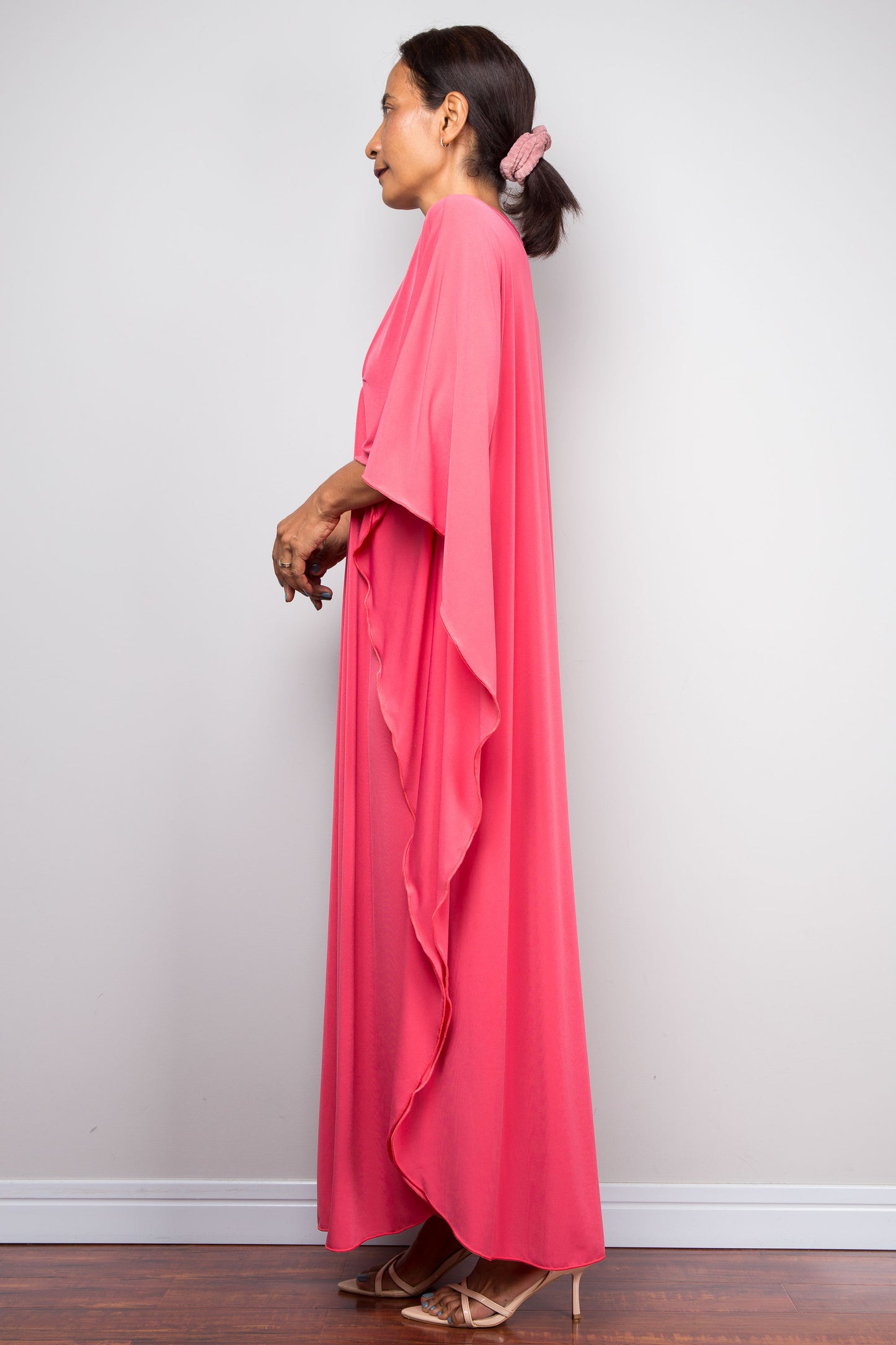 Side view of model in solid pink petite caftan dress with fluid butterfly sleeves.