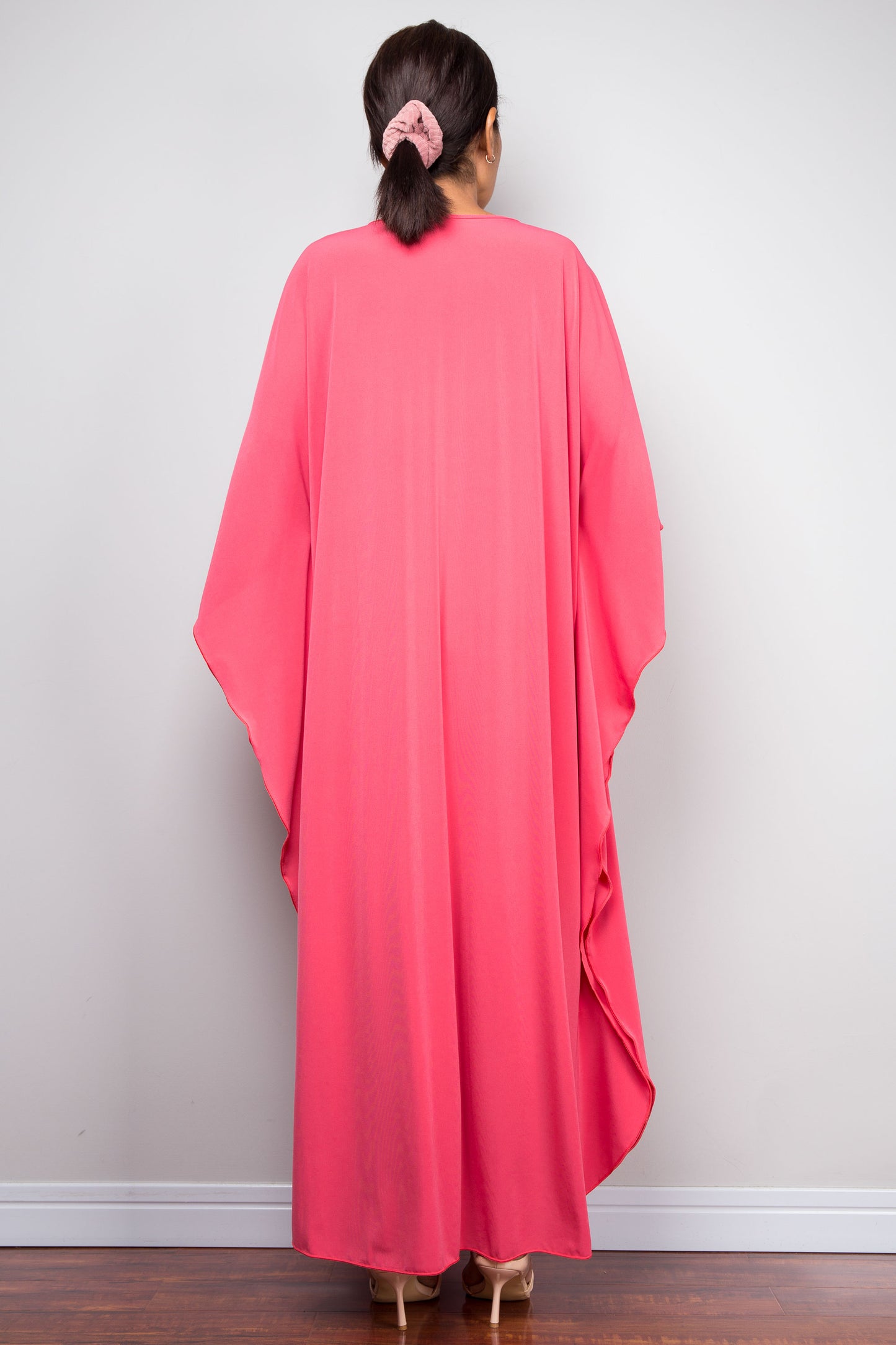 Back view of model in solid pink petite caftan dress with fluid butterfly sleeves