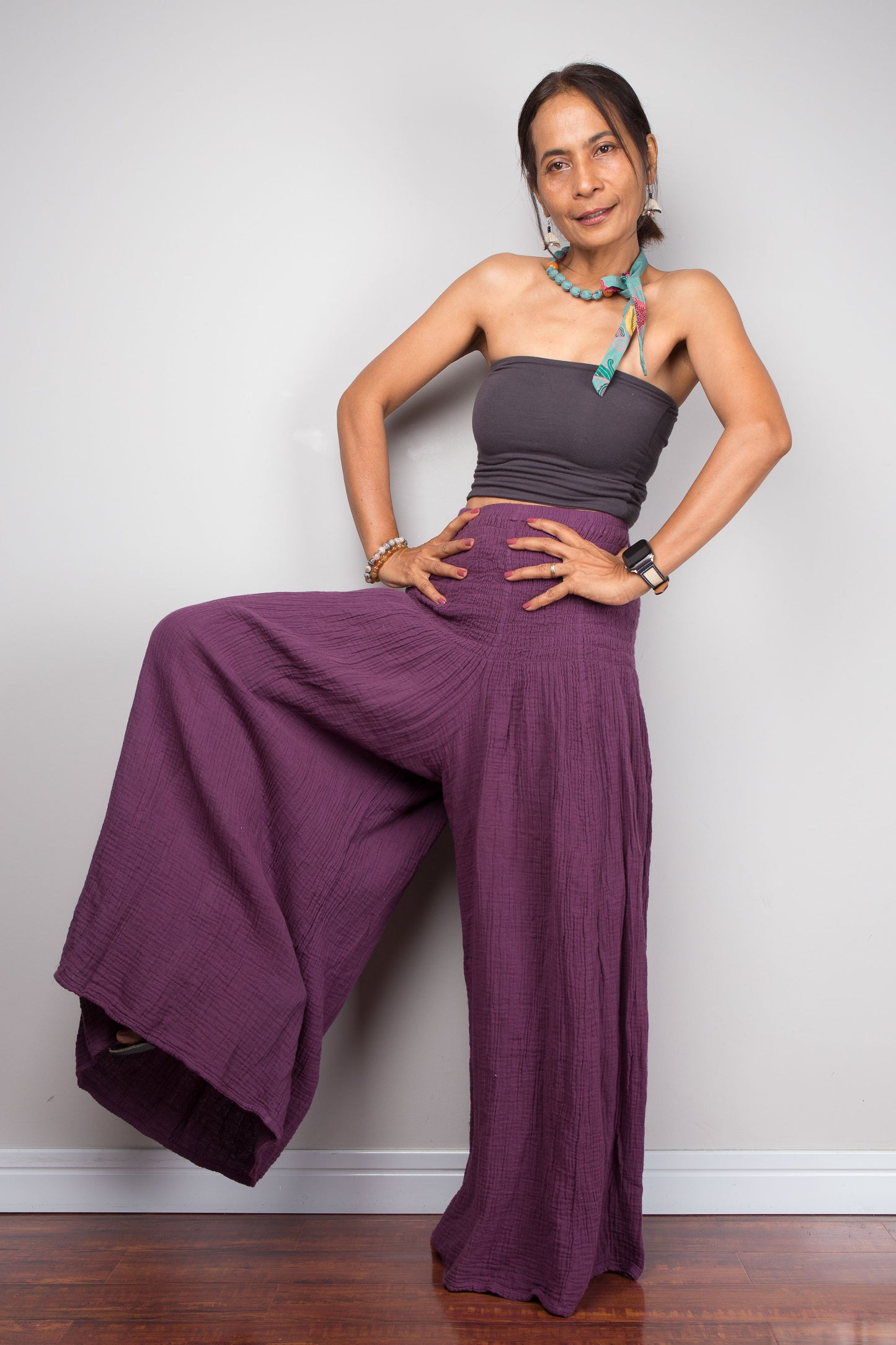 Woman wearing a purple outfit with wide-leg pants against a plain background