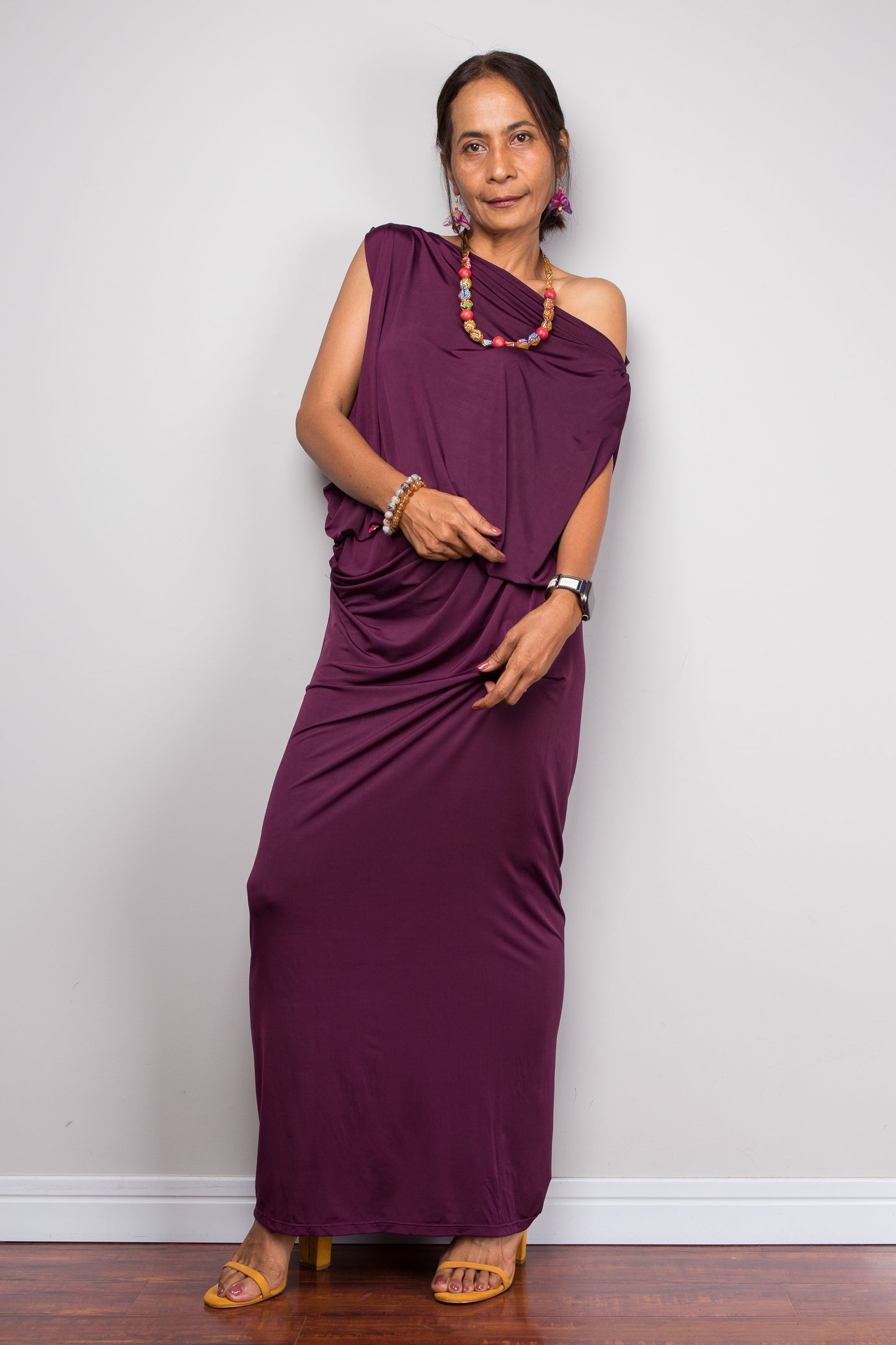 Woman wearing a purple one-shoulder dress against a plain background