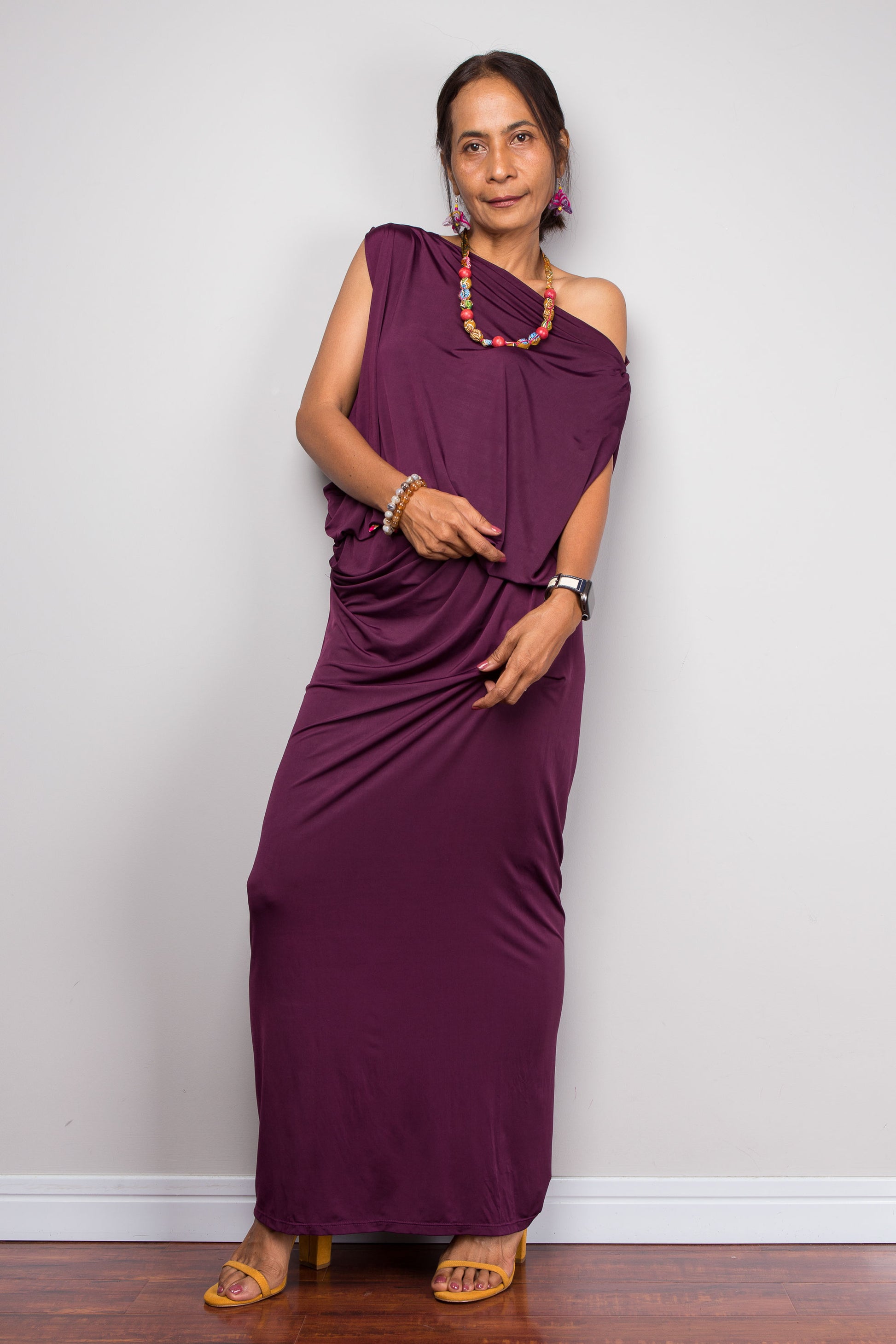 Woman wearing a purple one-shoulder dress against a plain background