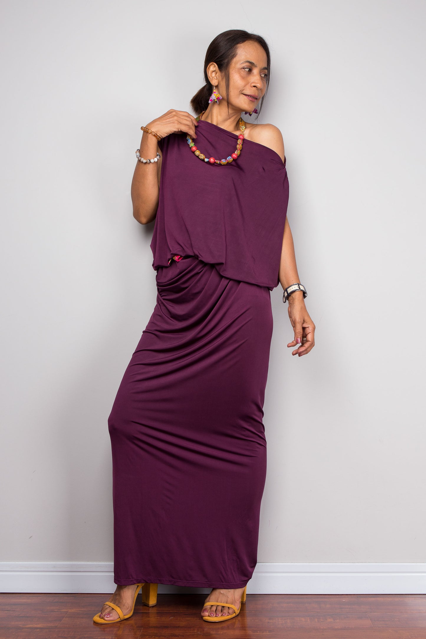 Woman wearing a purple one-shoulder dress against a plain background