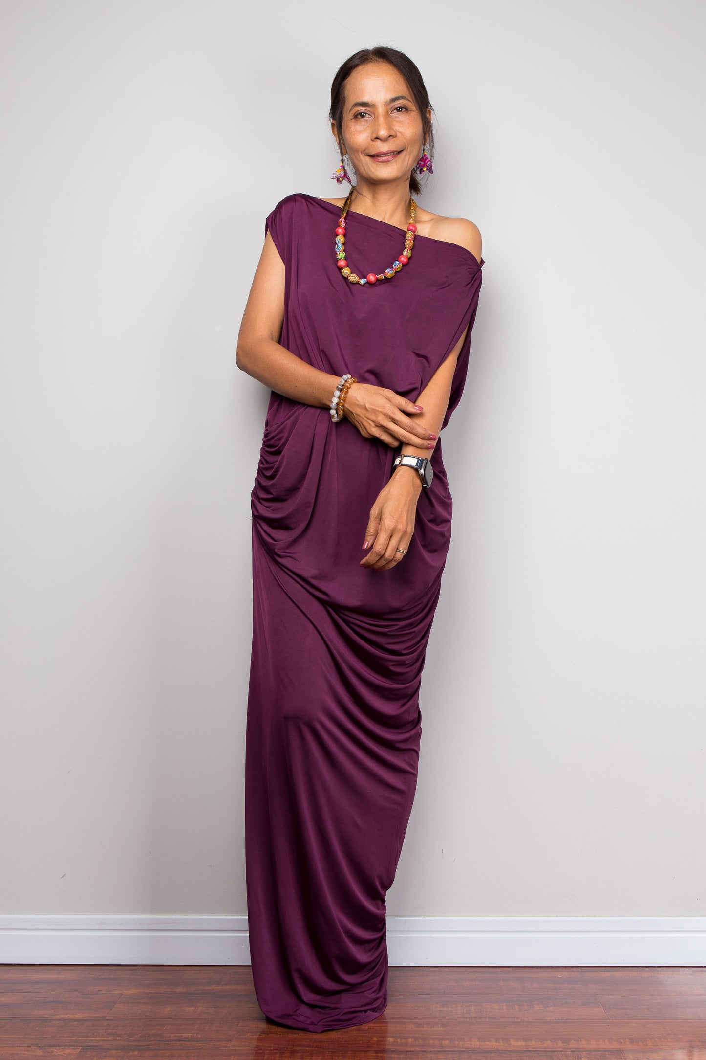 Woman wearing a purple one-shoulder dress against a plain background