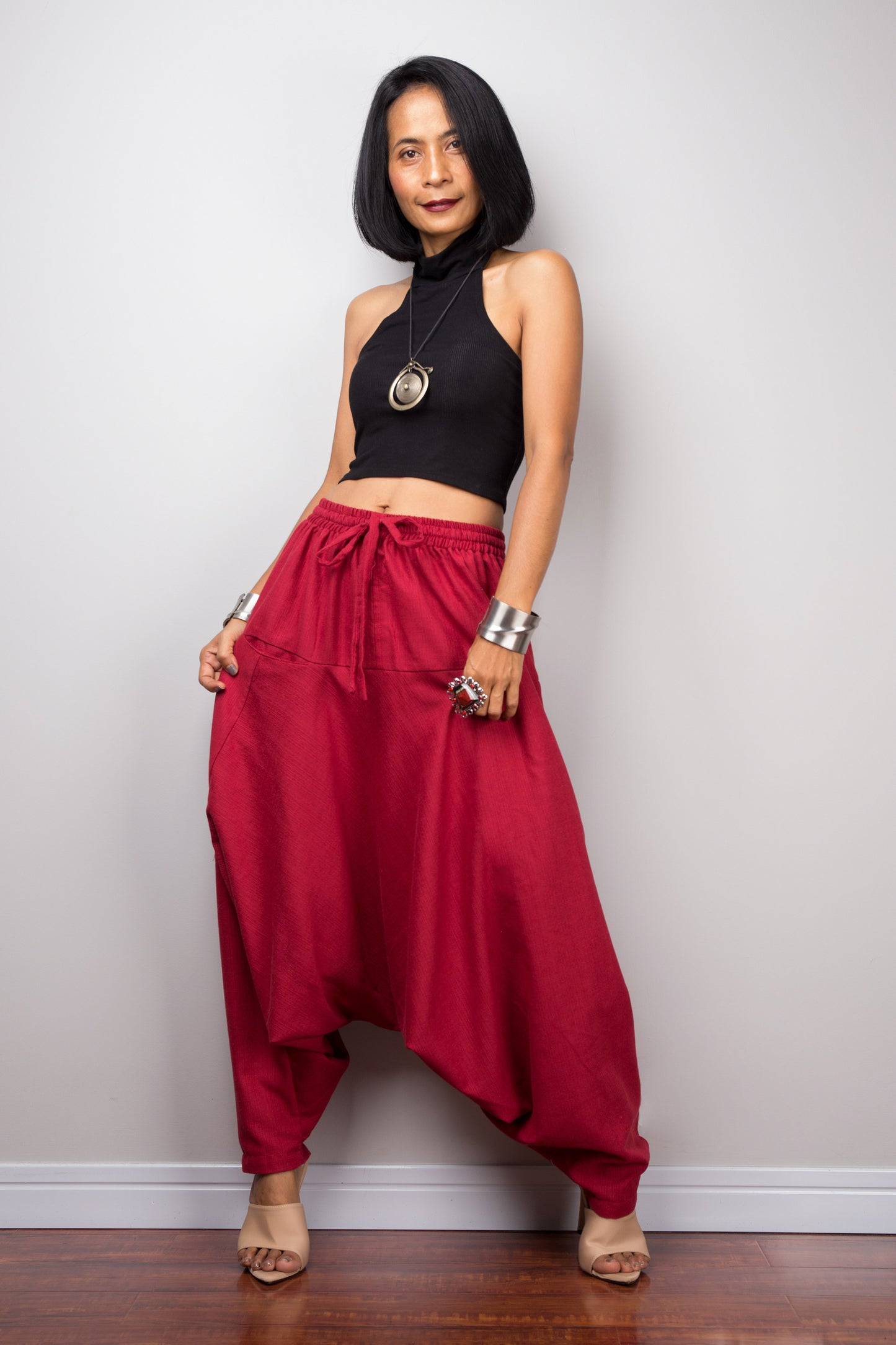 Model wearing red harem pants with a loose fit, standing against a plain background, showcasing the full-length view.