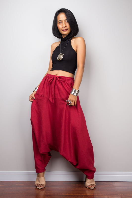 Model wearing red harem pants with a loose fit, standing against a plain background, showcasing the full-length view.