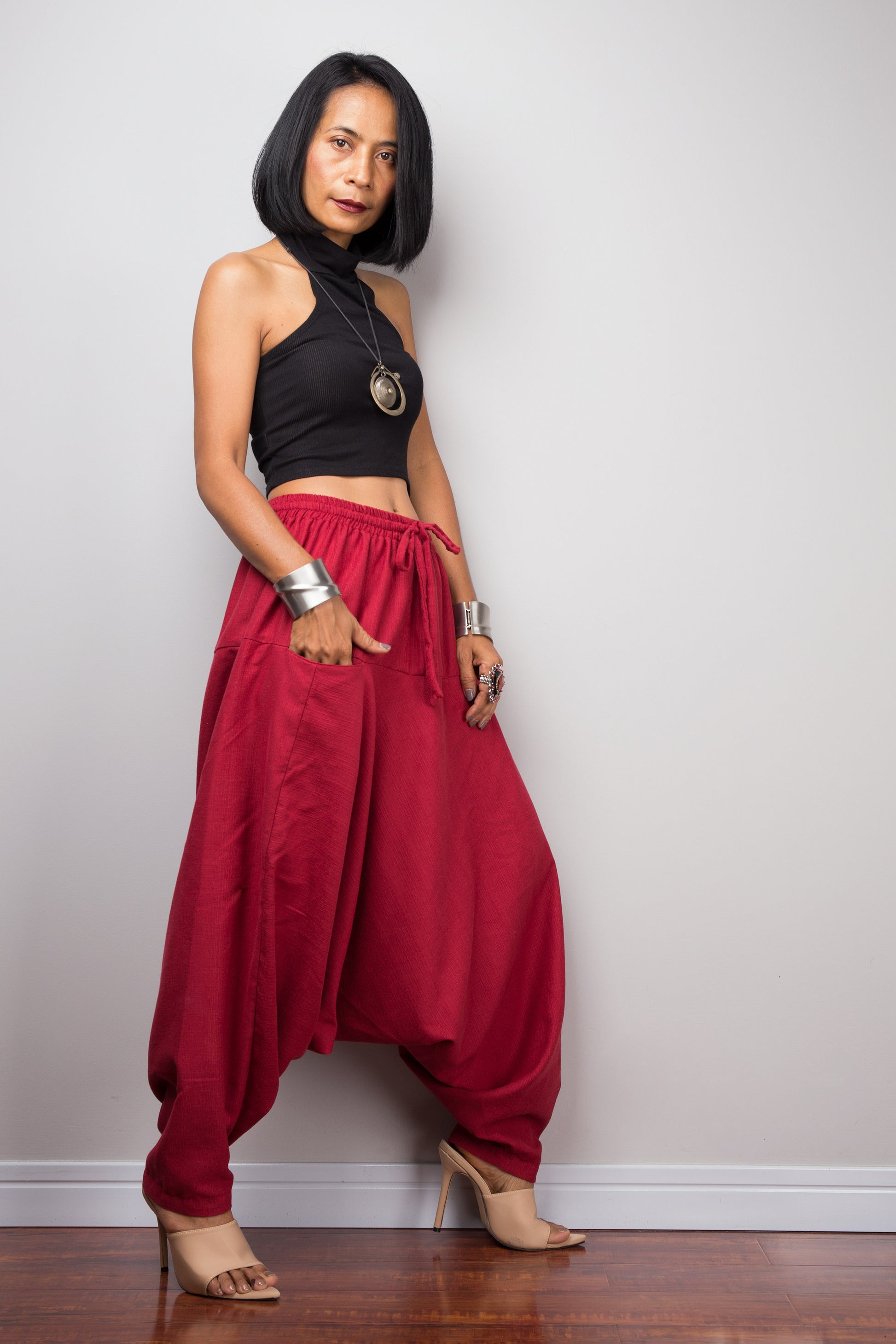 Side view of the red harem pants, displaying the loose fit and the flow of the fabric from the waist to the hem.